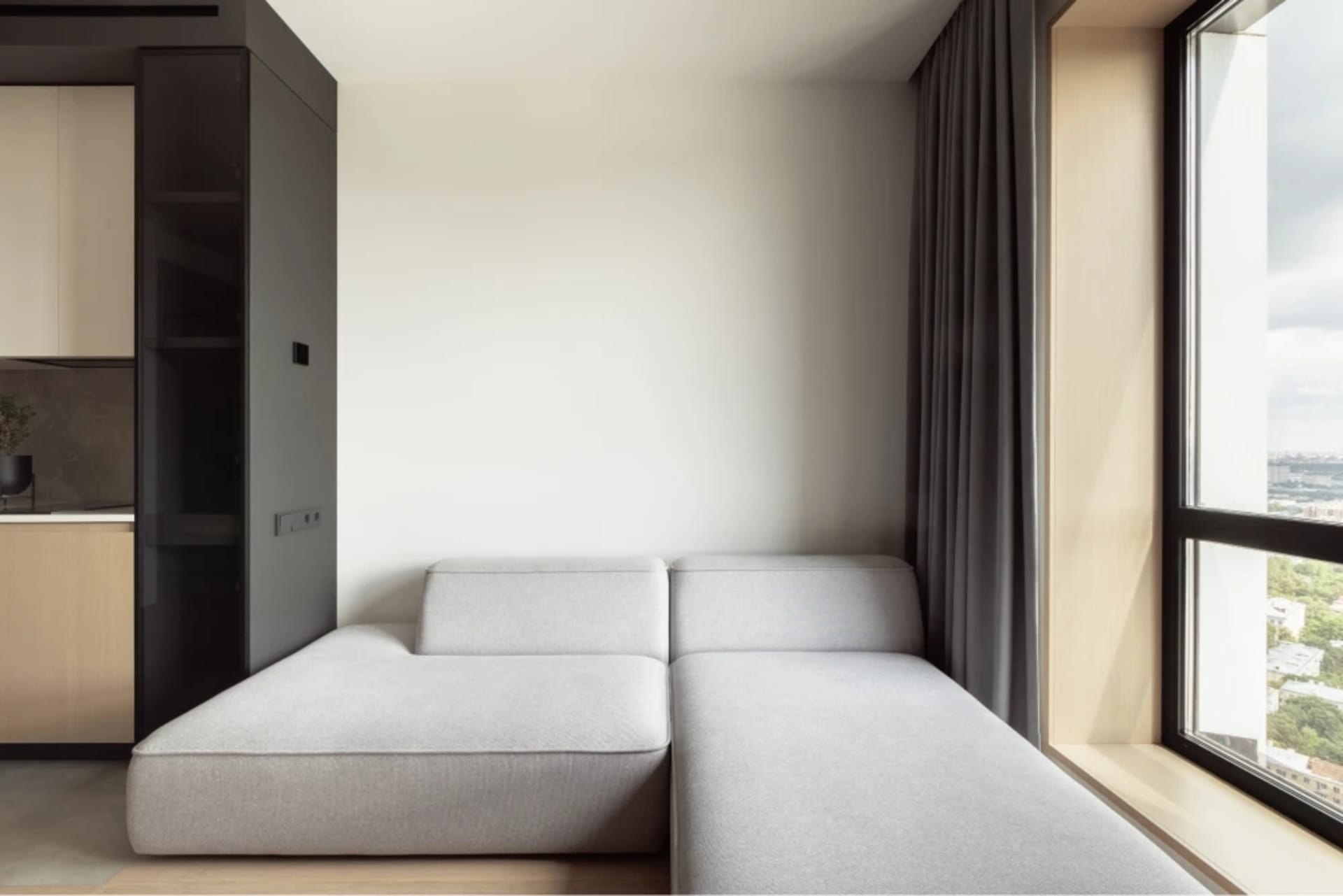 Modern living room featuring a fabric sofa and large windows with a view of the outdoors.