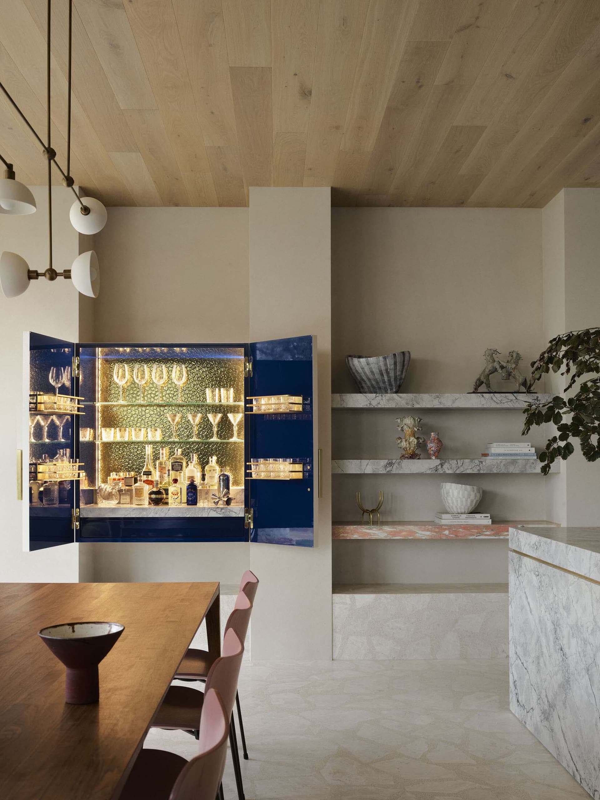 A modern interior design featuring a living room with a bar area equipped with marble, concrete, and wooden elements.
