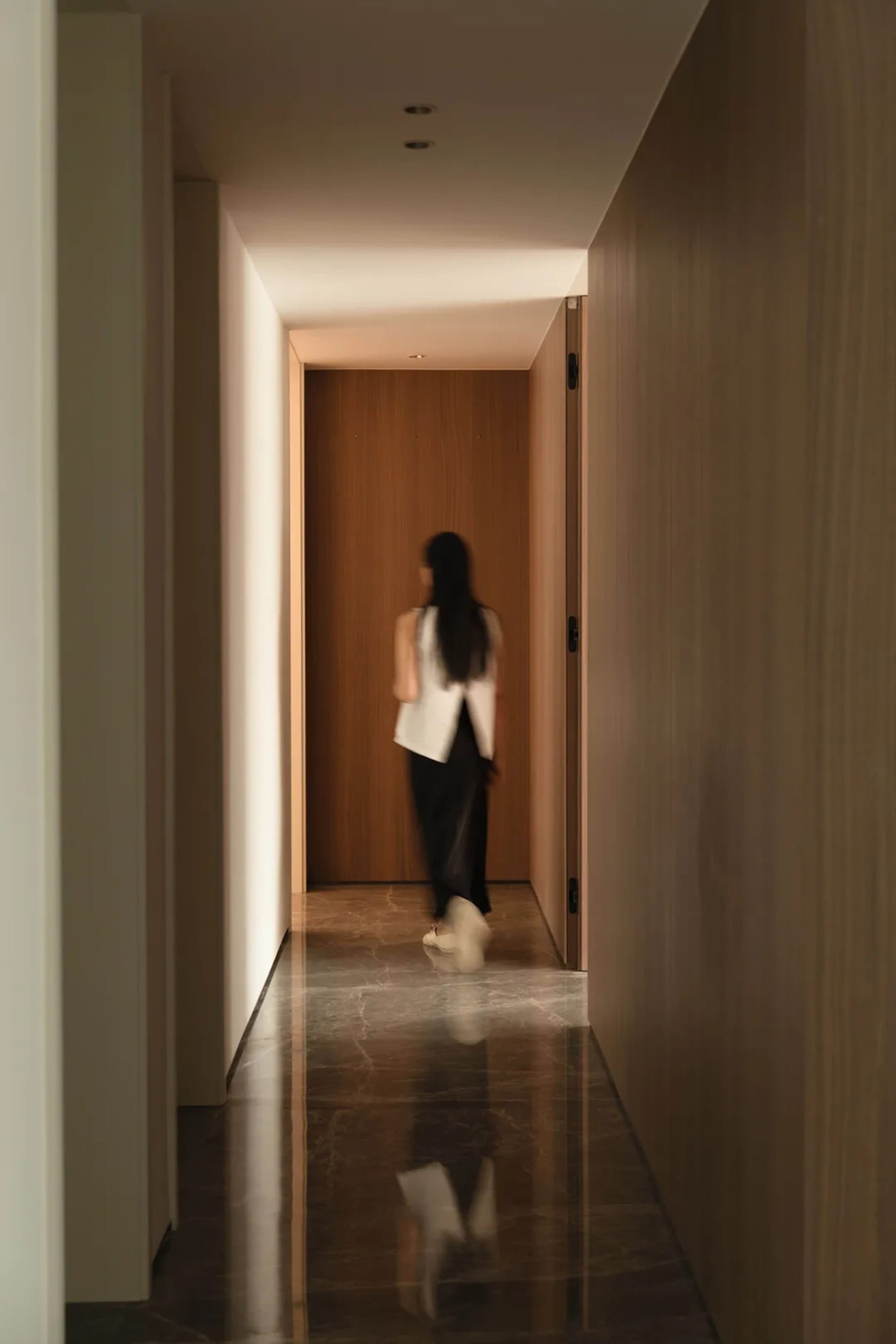 A modern minimalist hallway with marble and wood materials