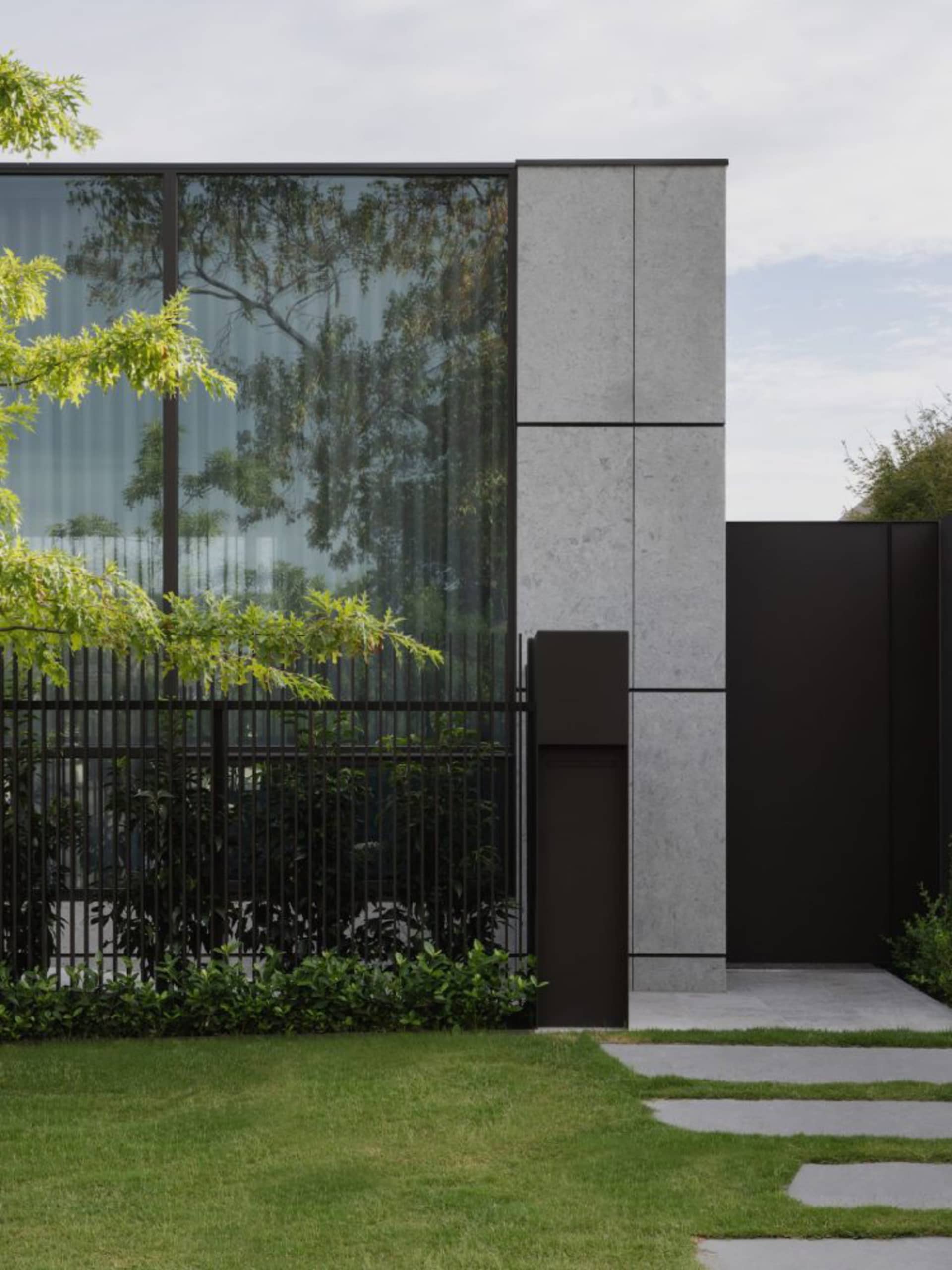 Modern minimalist house featuring glass walls, concrete panels, and metal accents.