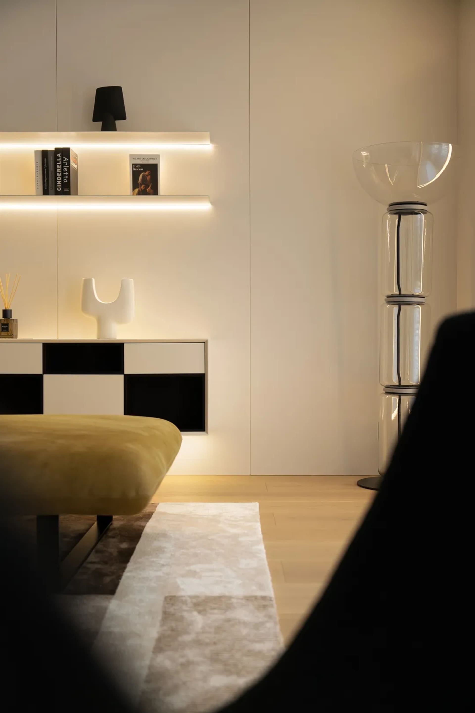 A modern living room featuring wooden flooring, glass walls, and leather seating with metal accents.