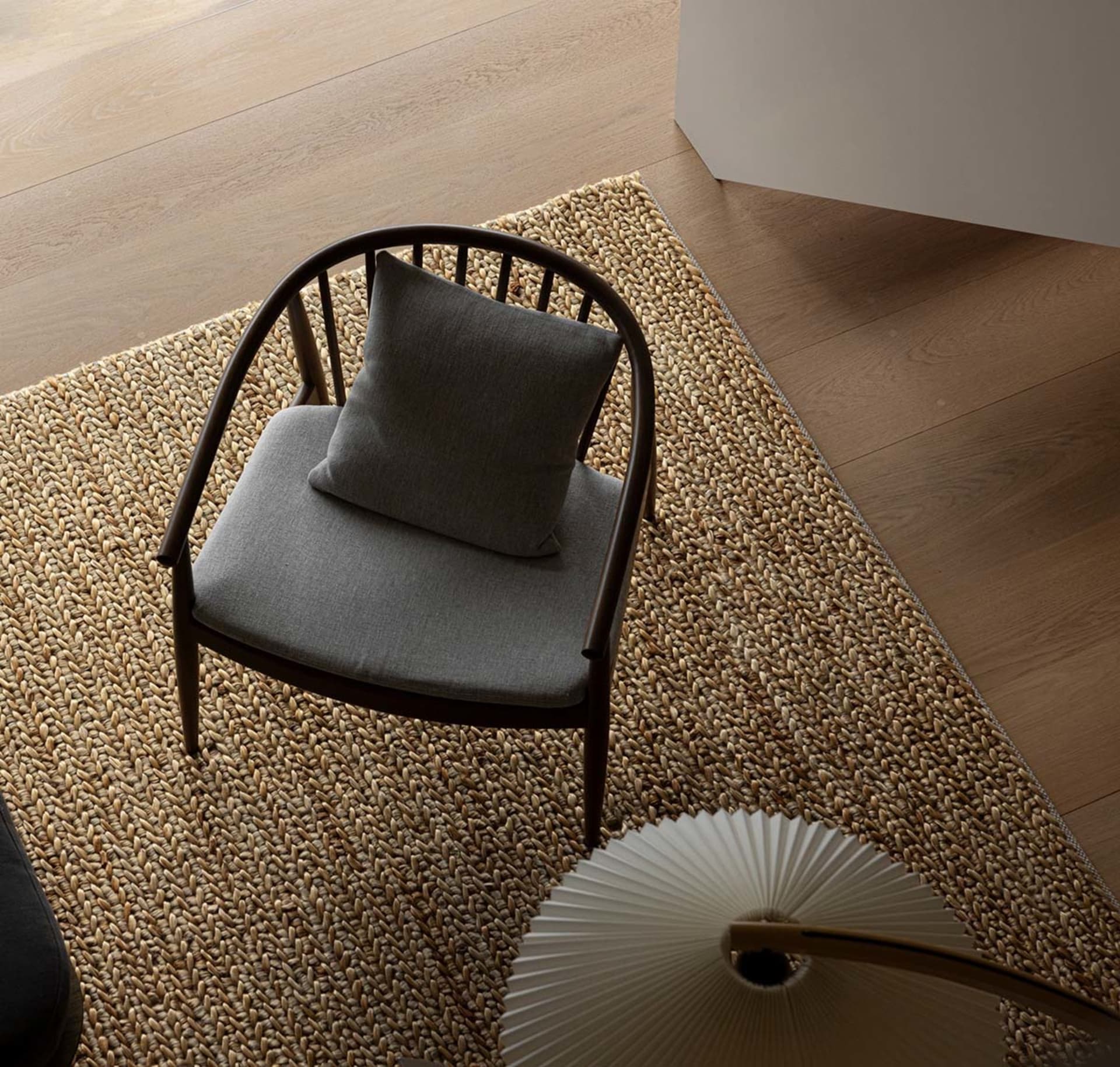 A gray cushion on a wooden chair in a minimalist living room setting.