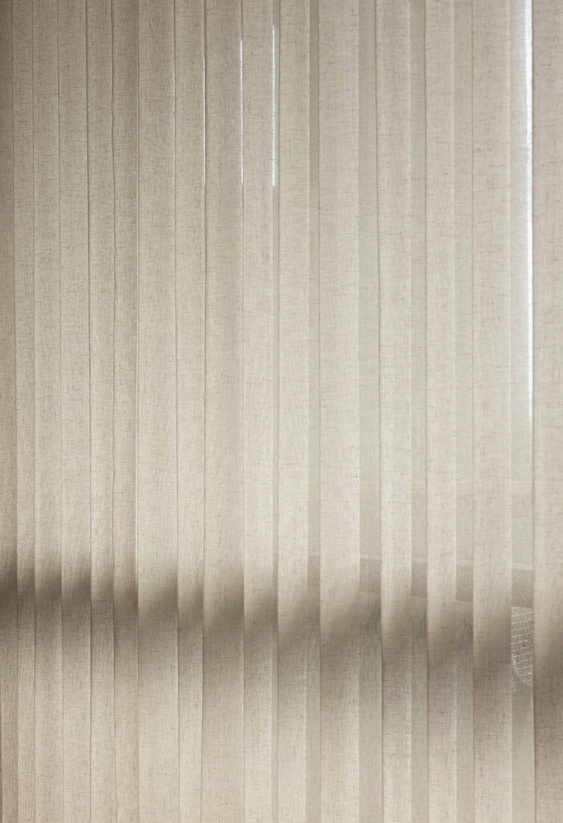 Striped taupe textile curtain hanging in a window.