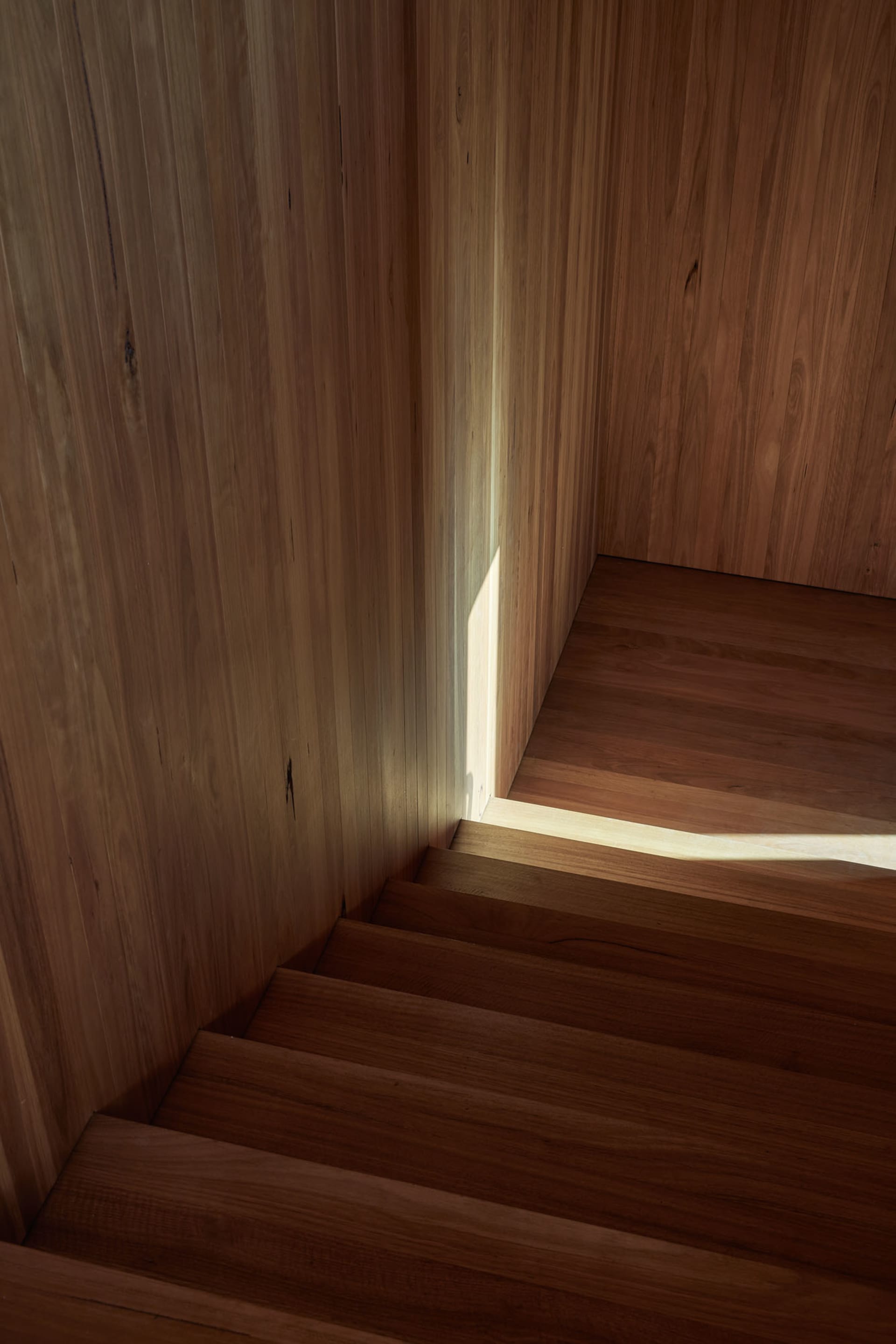A wooden staircase with sunlight filtering through, creating a warm and inviting atmosphere.