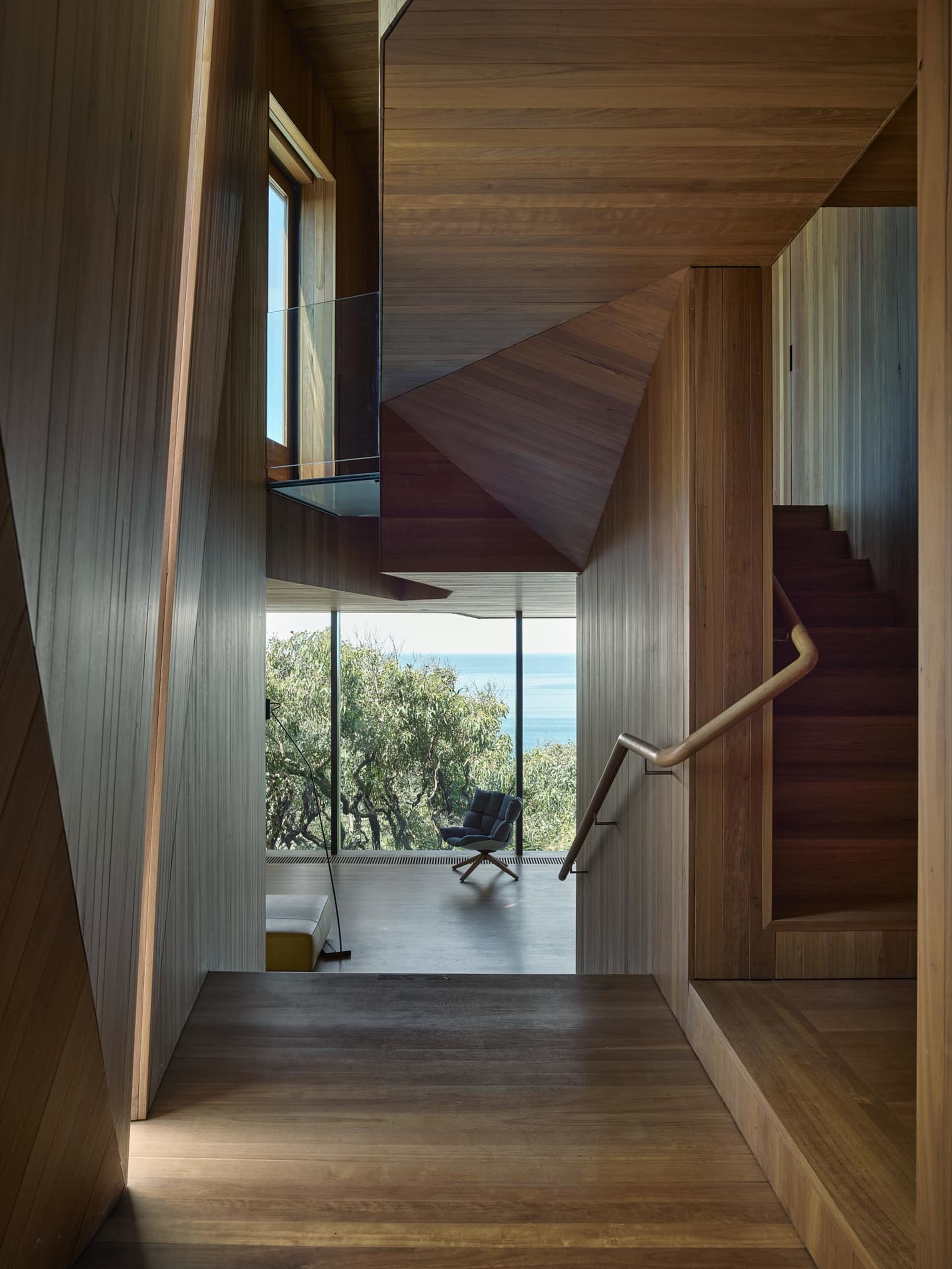 Modern residential interior featuring a wooden staircase overlooking the ocean.