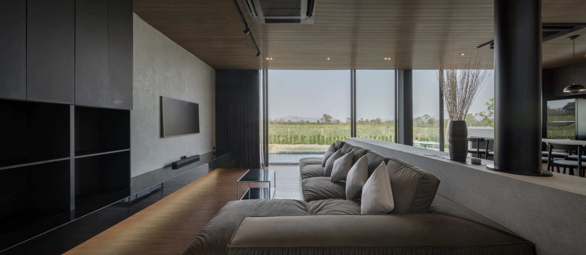 A modern living room featuring a concrete and glass sofa with a large floor-to-ceiling window.