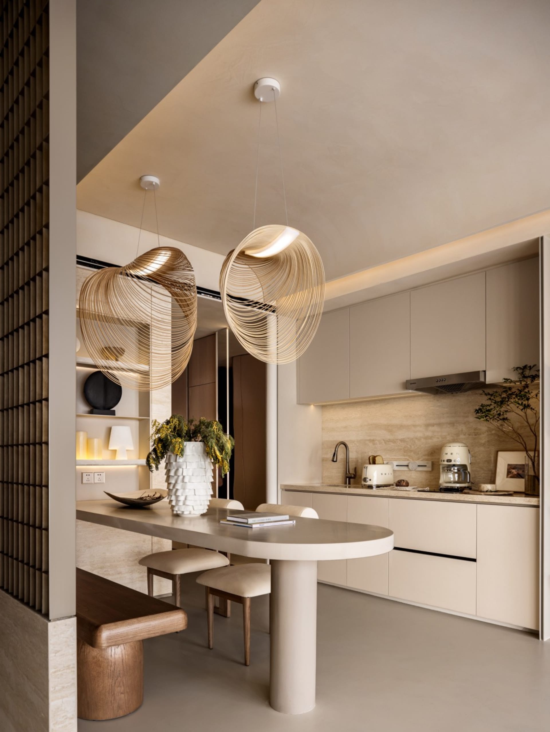 A modern minimalist kitchen featuring sleek, white countertops and a central island with a concrete pillar base. The space in