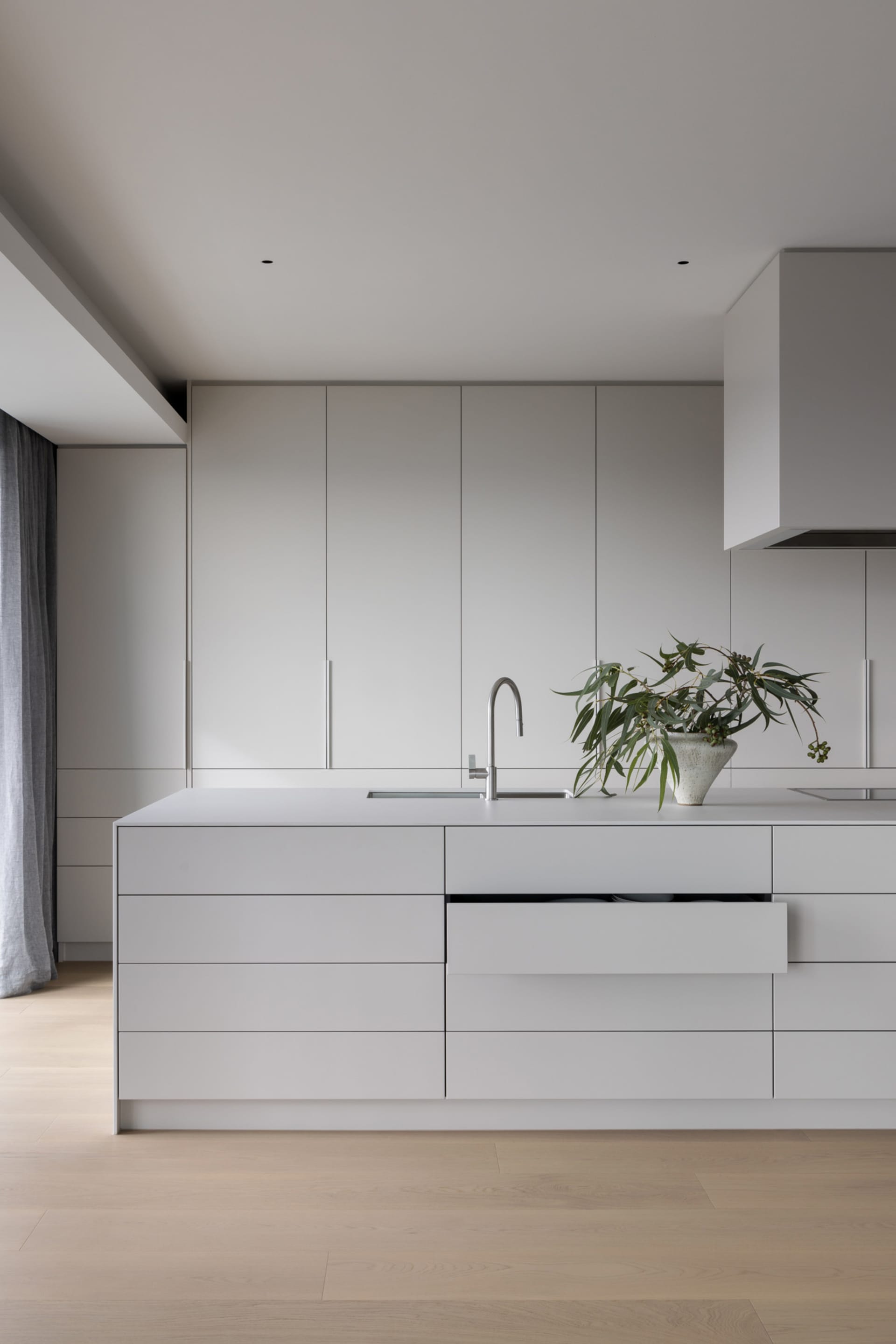 Modern minimalist kitchen with grey cabinets and white countertops.