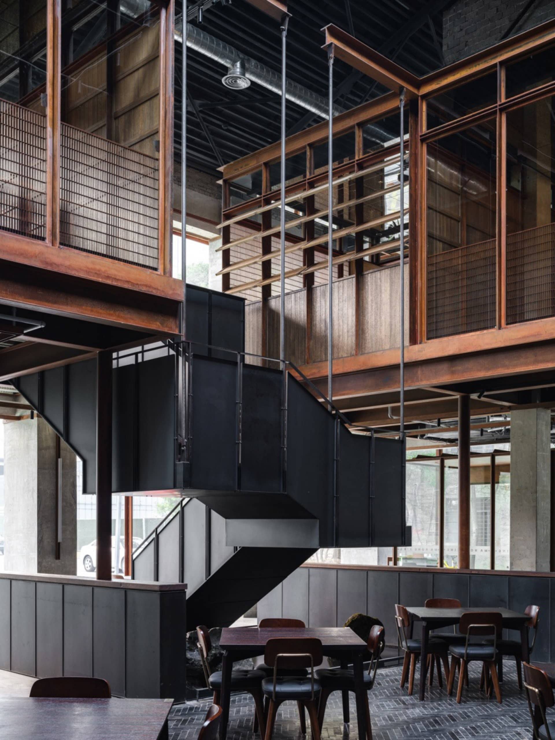 Industrial-style interior space featuring black metal structures, wooden panels, and glass elements.
