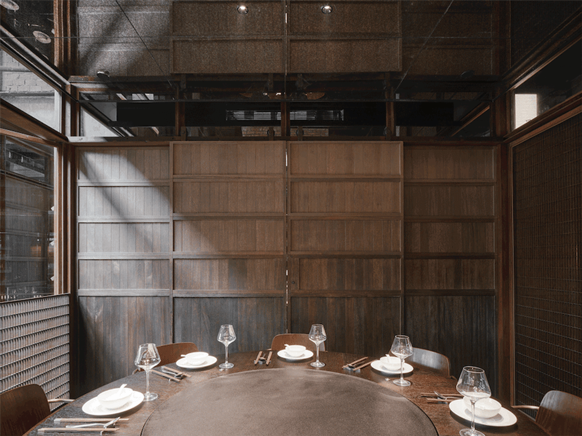 A modern restaurant interior with wooden walls and circular table arrangement.