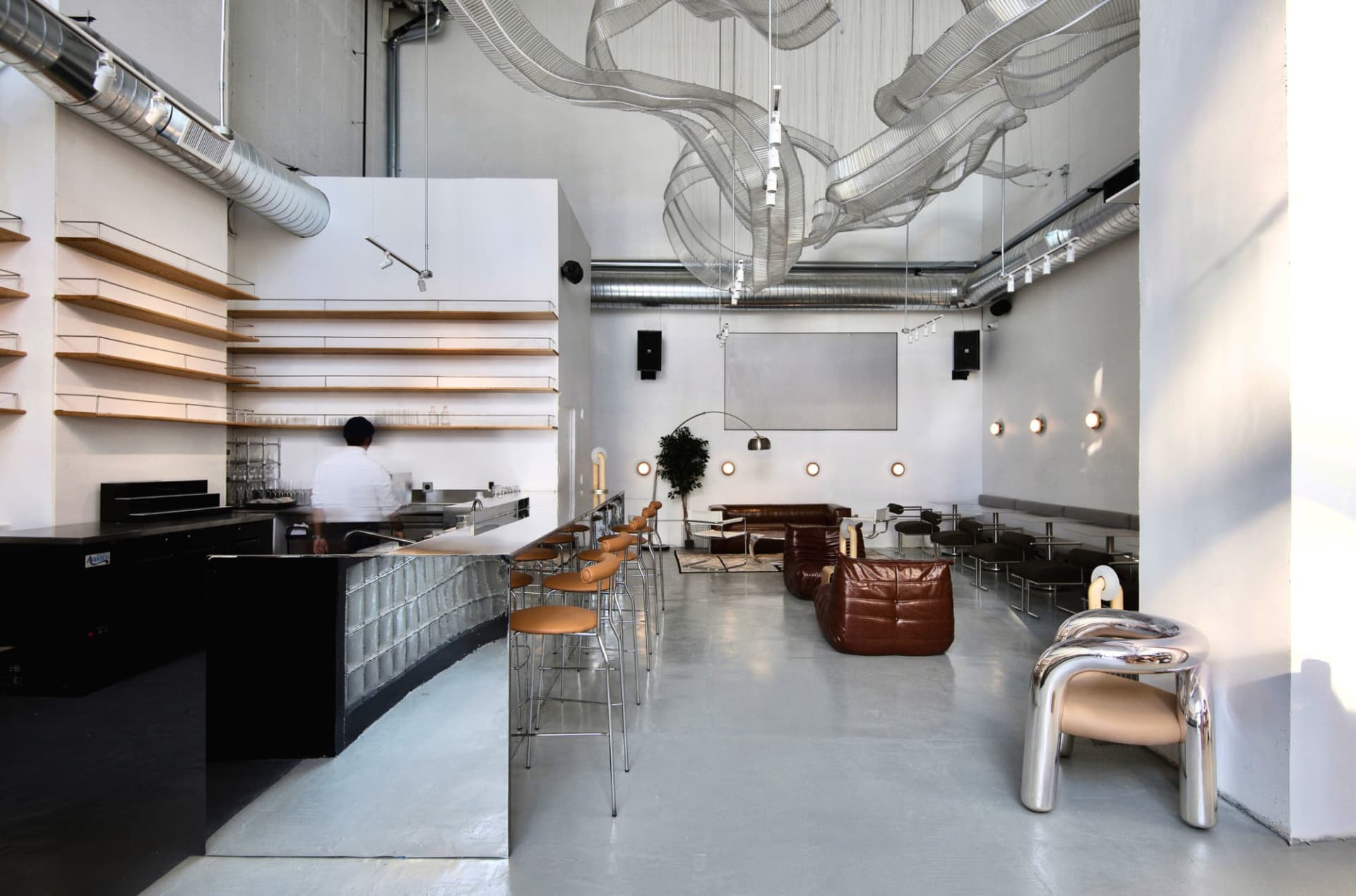 Modern industrial restaurant bar with concrete floor and minimalist design.