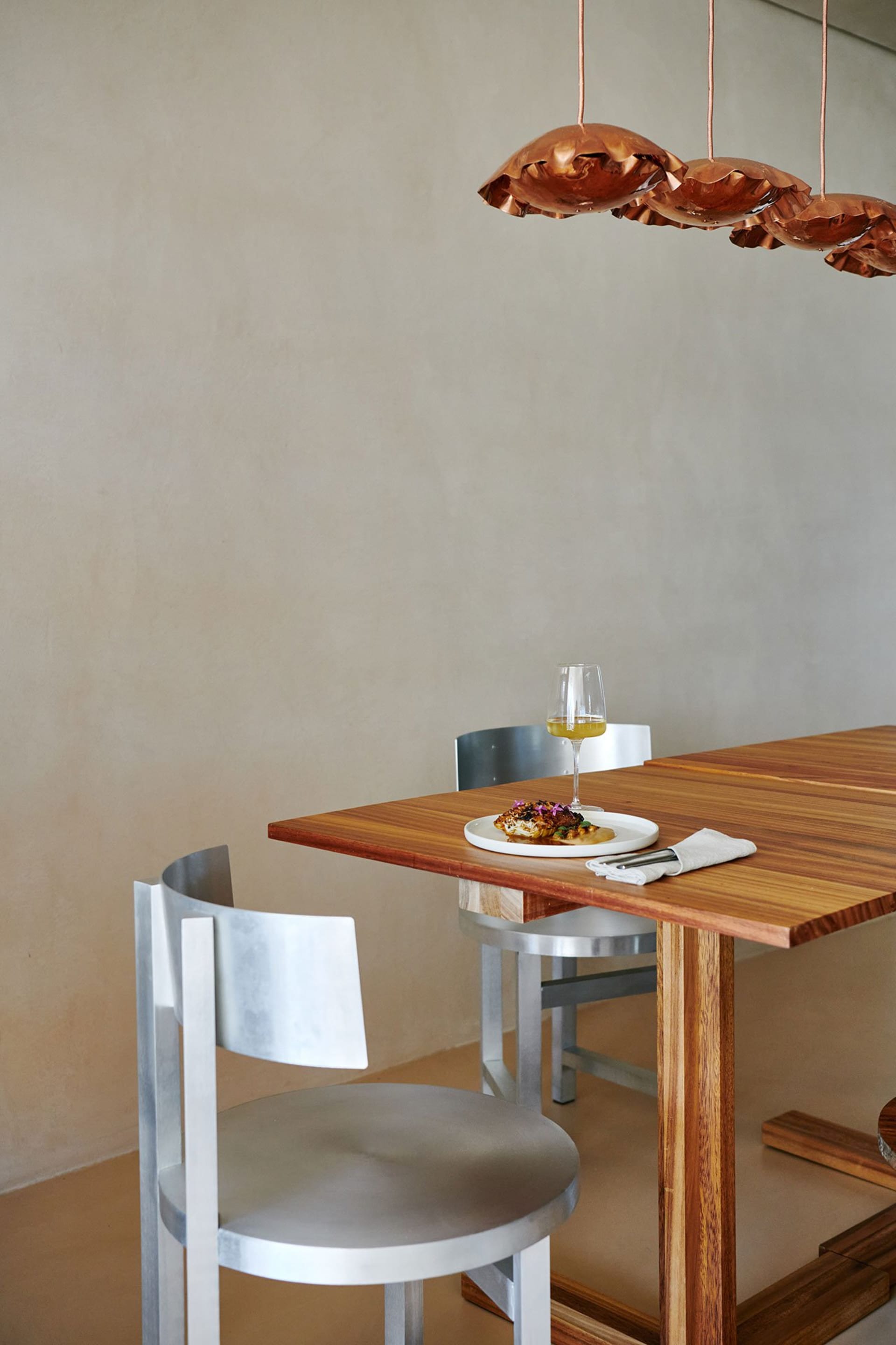 A modern dining room features a wooden table with a plate of food and a glass of wine.
