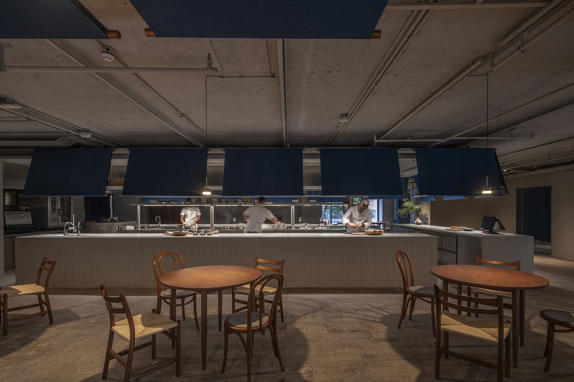 A spacious restaurant kitchen with dark blue countertops, concrete flooring, and a large central island.