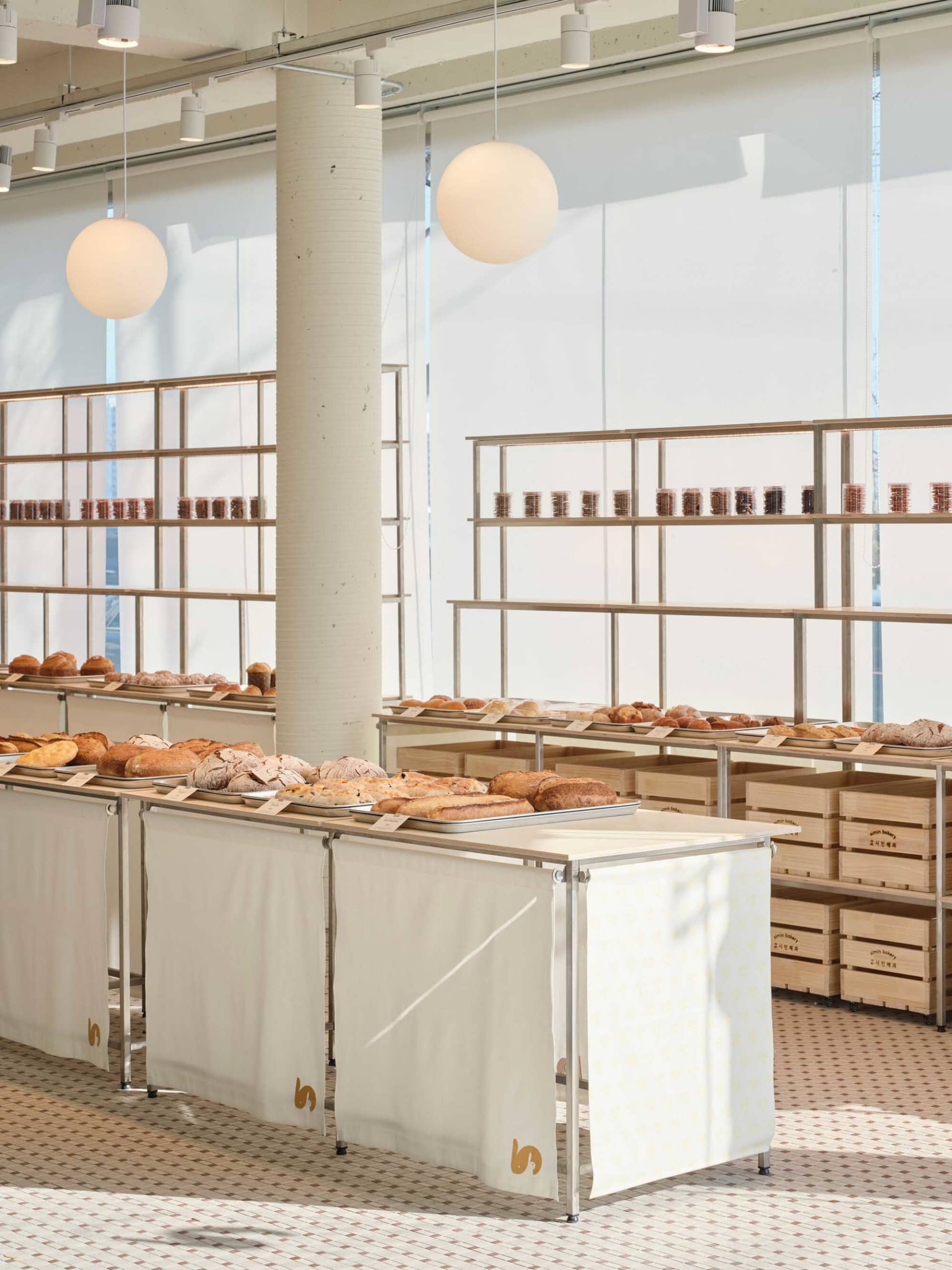A bakery featuring various breads displayed on tables and shelves with wooden crates and metal racks.