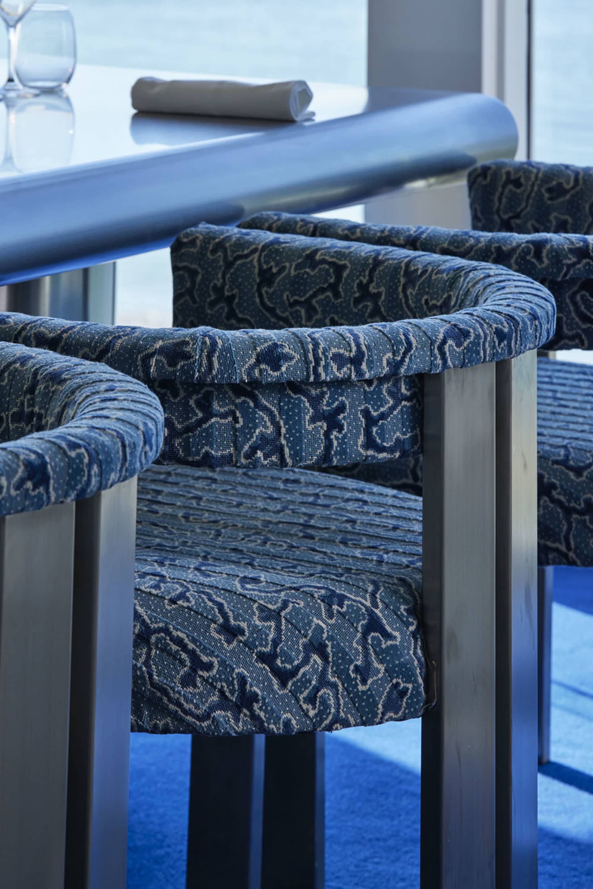 A minimalist barstool with a blue patterned fabric design.
