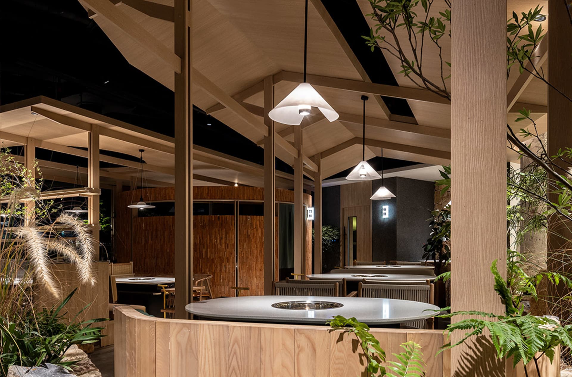 A modern restaurant interior featuring wooden tables and hanging lights.