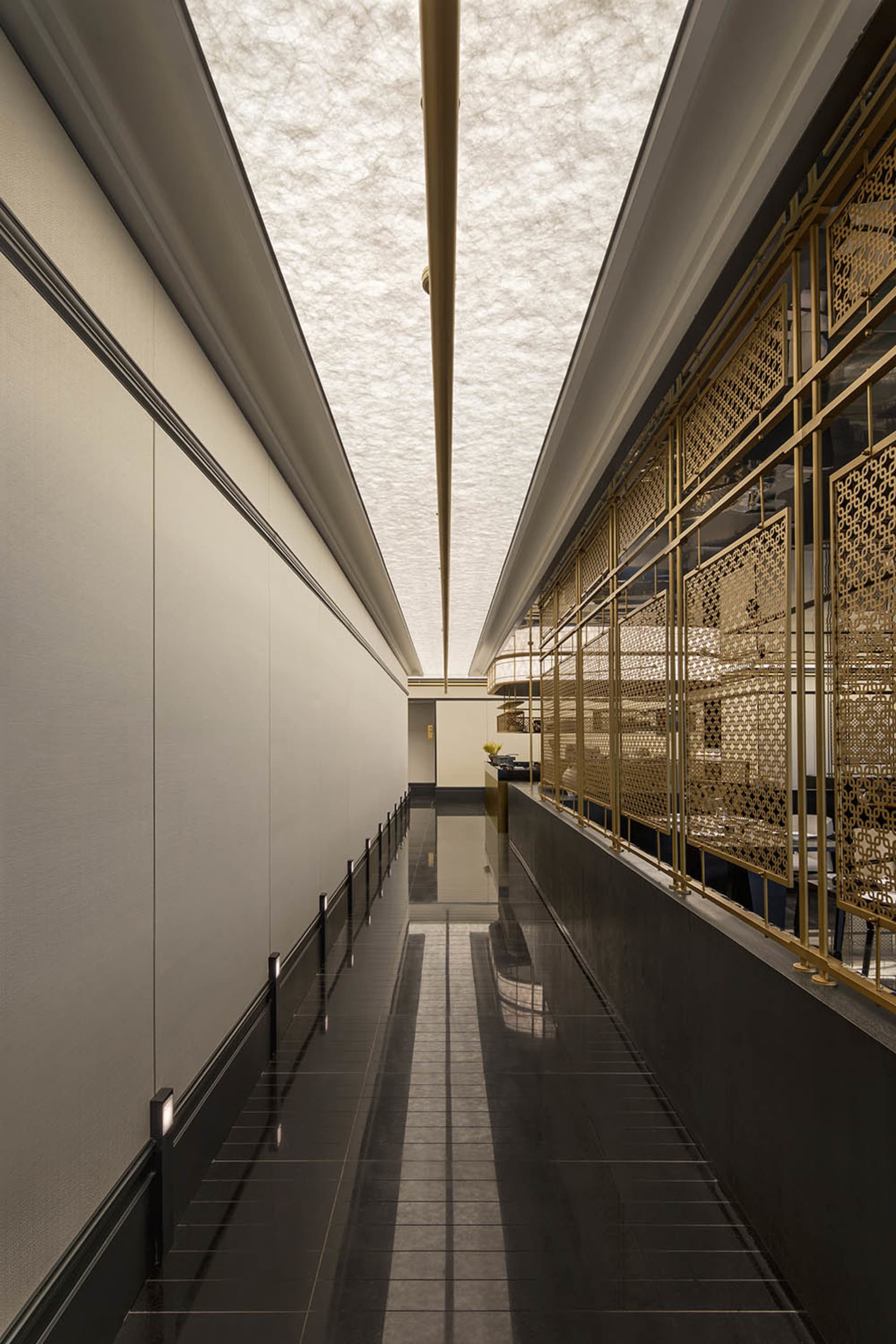 A modern interior design of a corridor featuring ceramic tiles and gold brass materials.