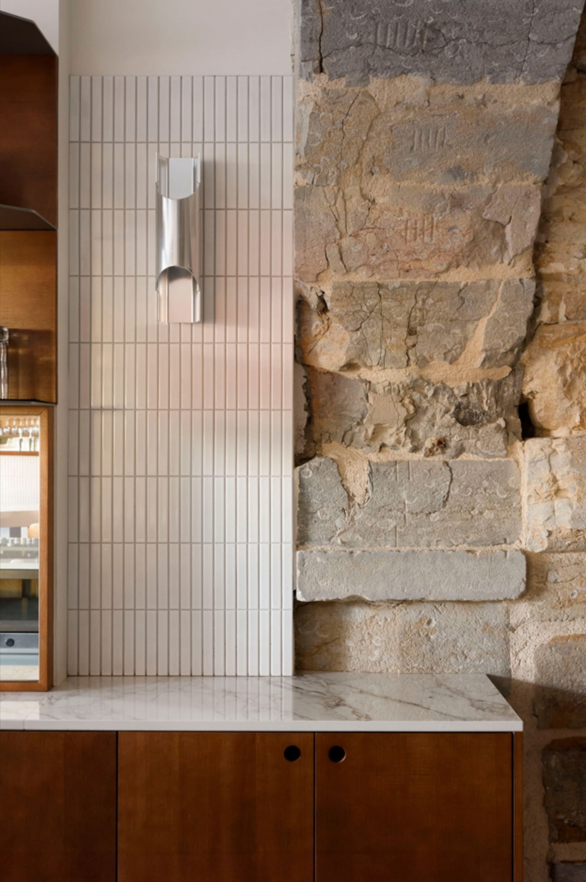 Modern kitchen featuring white tiled walls and concrete elements.