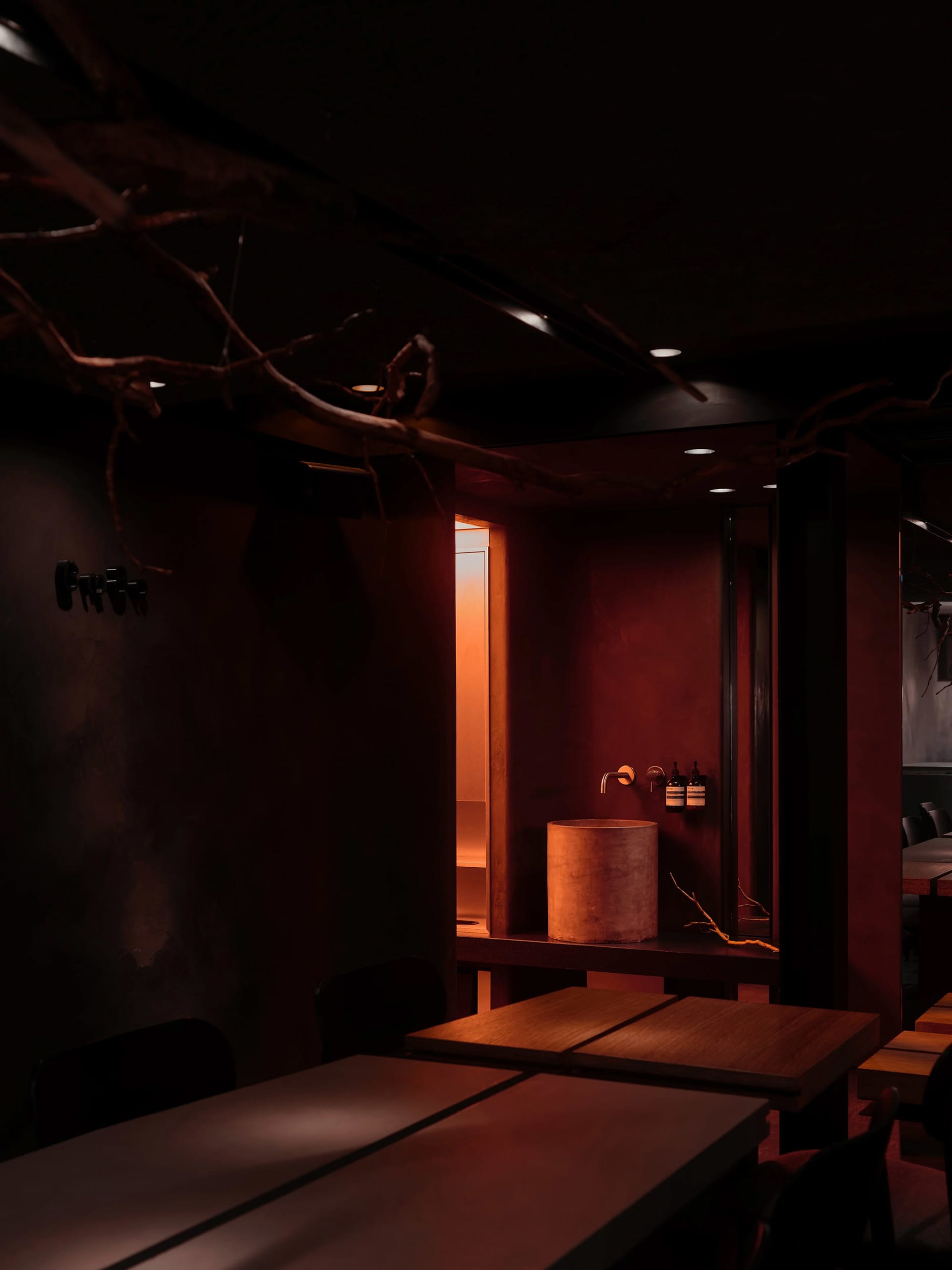 A modern minimalist restaurant interior with wooden, concrete, and metallic elements.