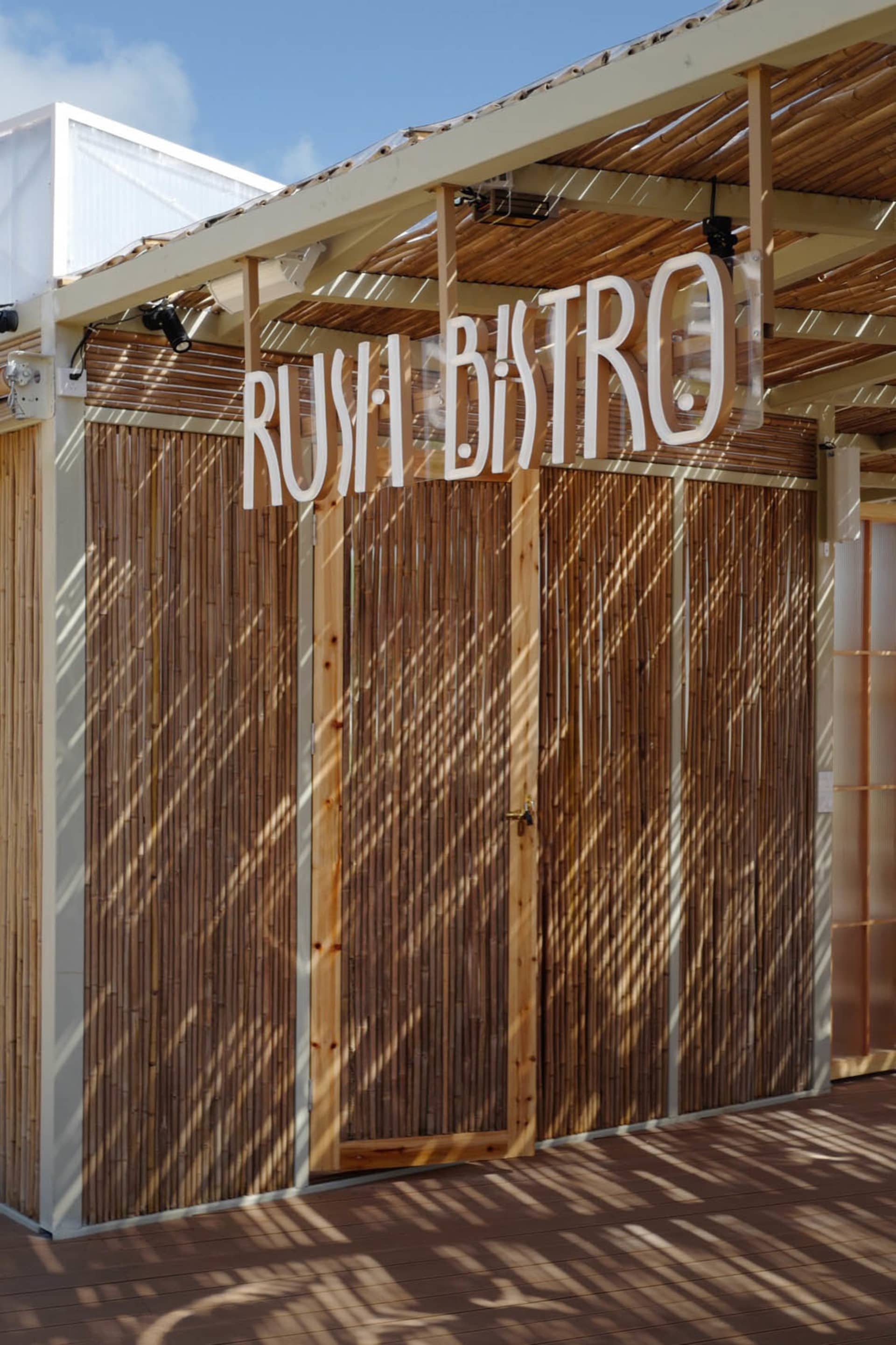 Bamboo exterior design of a restaurant with the sign 'Rush Bistro'.