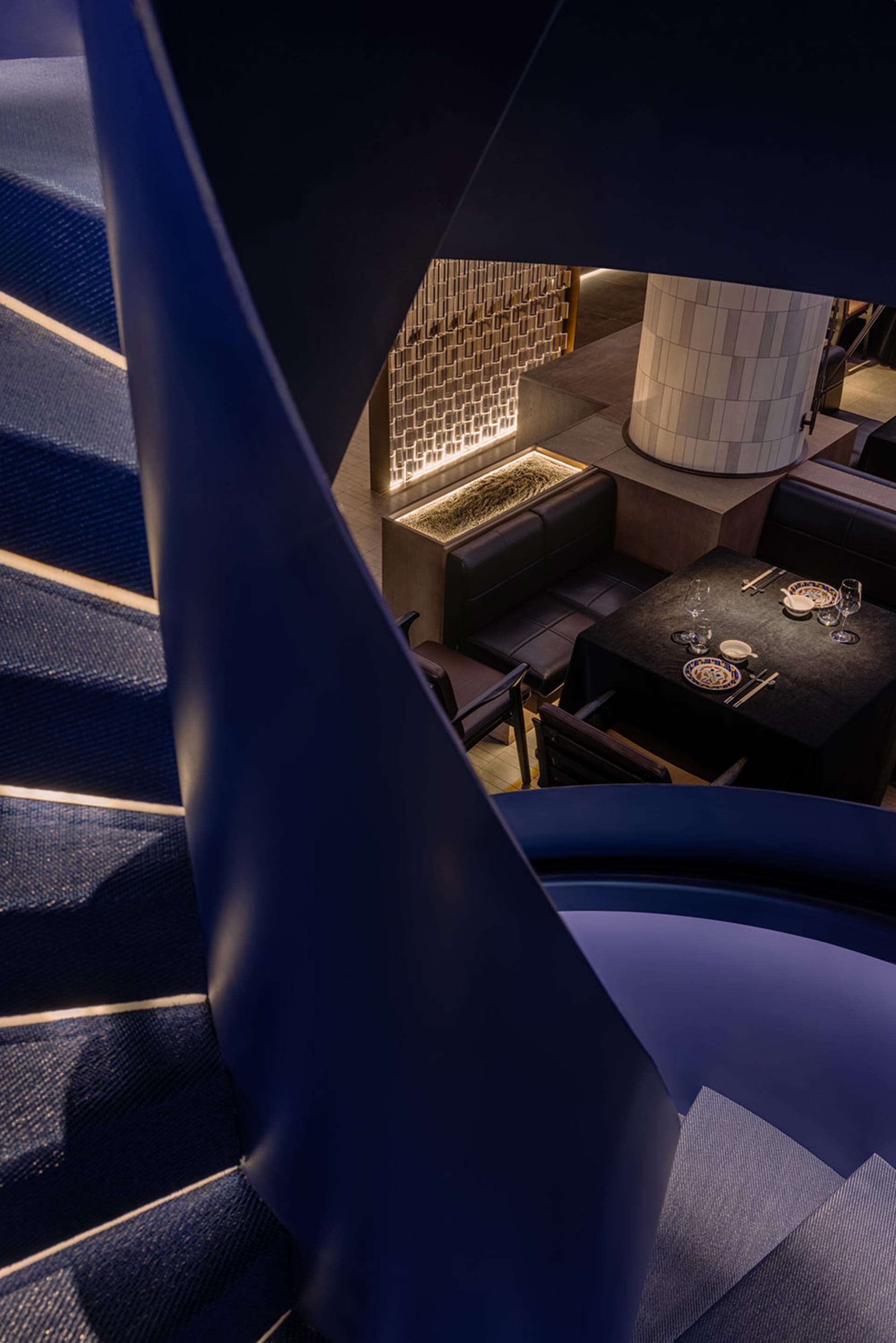 A modern restaurant interior with a metal staircase and marble flooring.