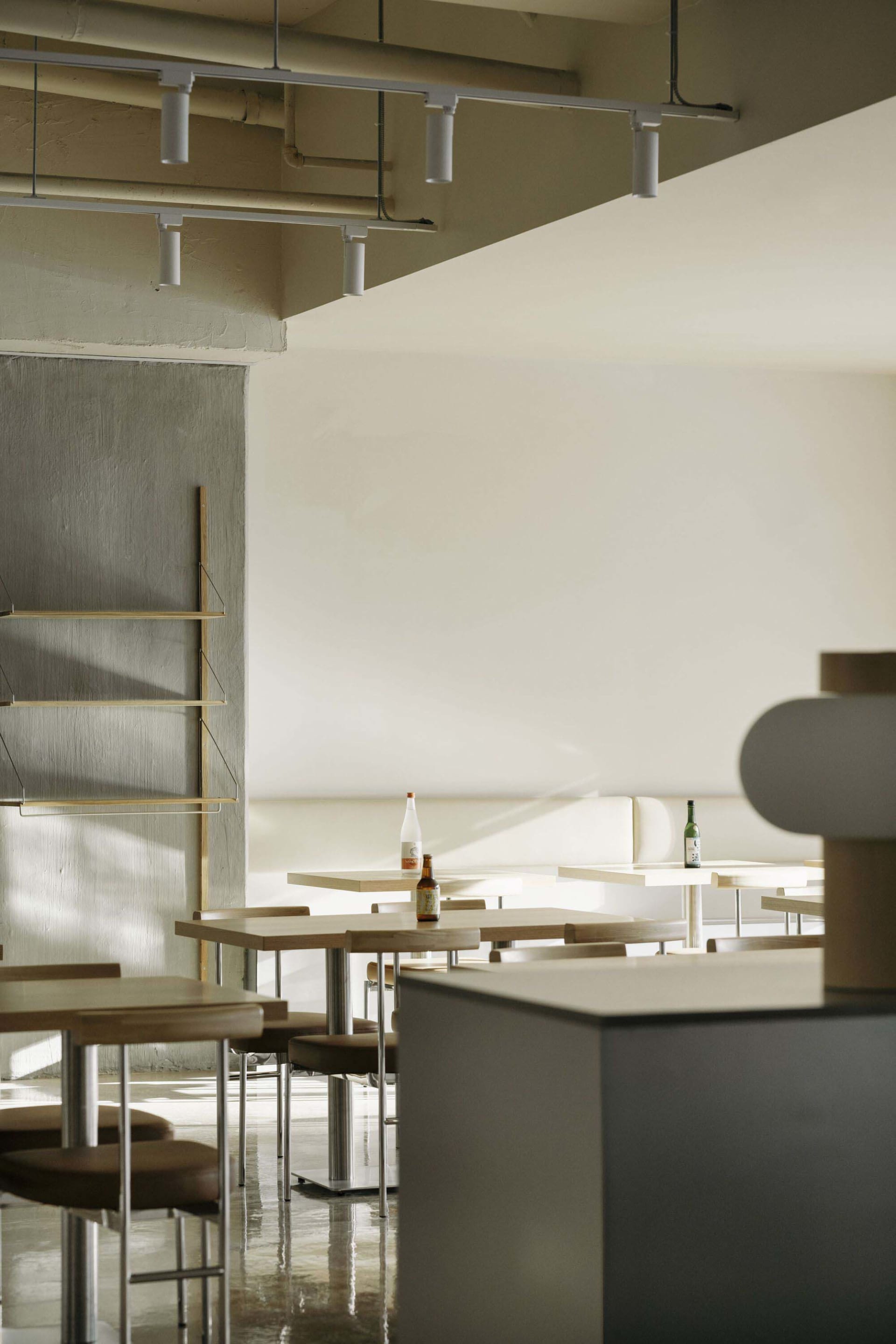 A modern restaurant interior featuring minimalist design, wooden tables, and concrete finishes.