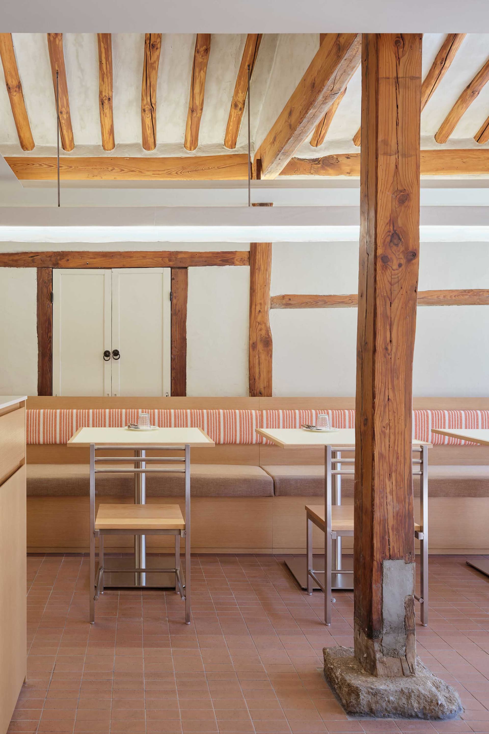 A modern restaurant interior with wooden tables, chairs, and built-in seating.