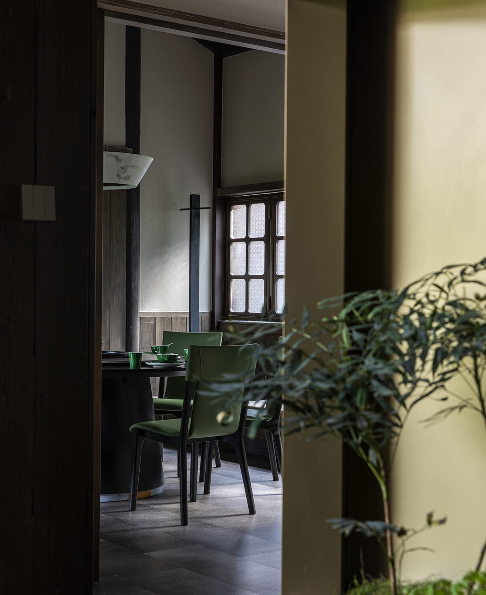 A modern dining room with green plastic chairs and a dark wooden table.
