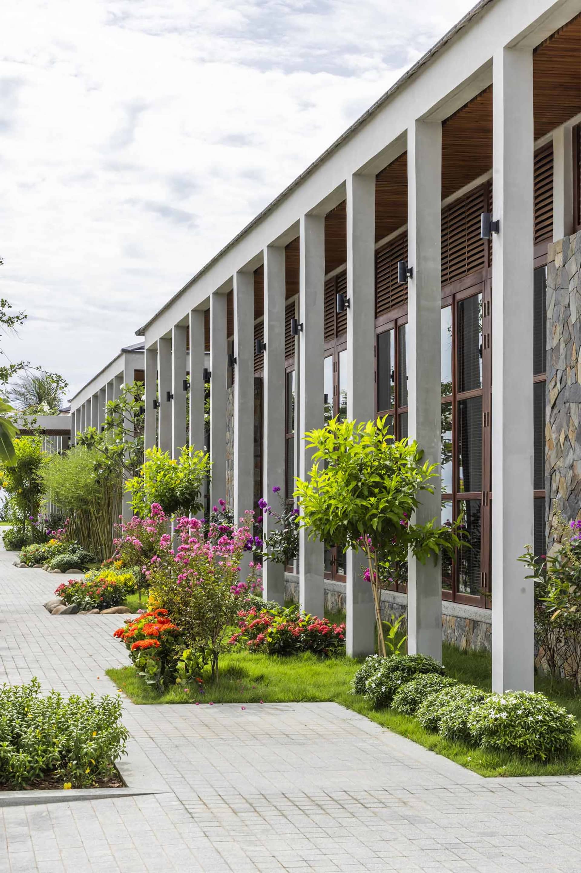 Modern hotel exterior featuring tall concrete columns and a vibrant garden space