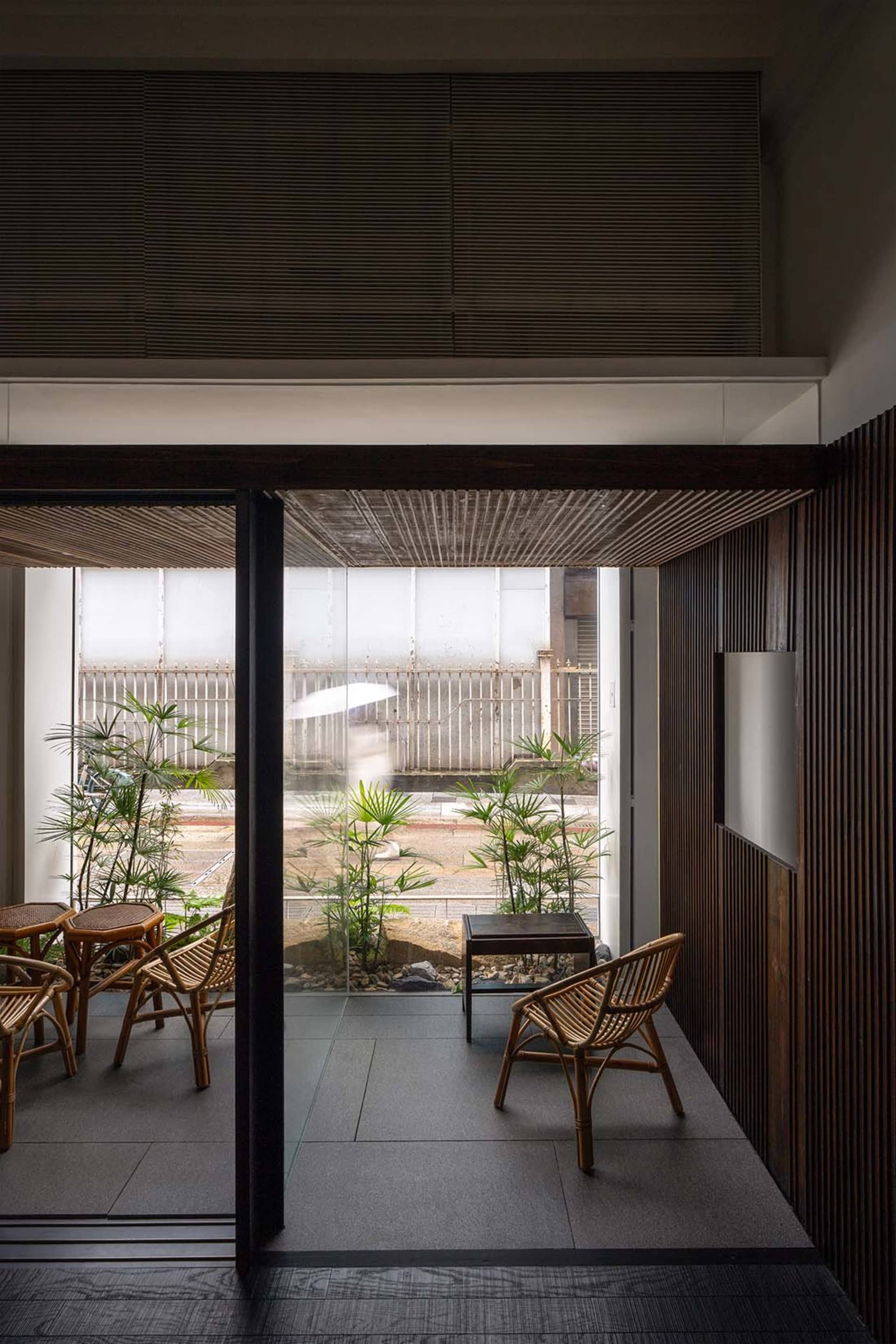 Cafe interior with wooden walls, plants, and rattan furniture.