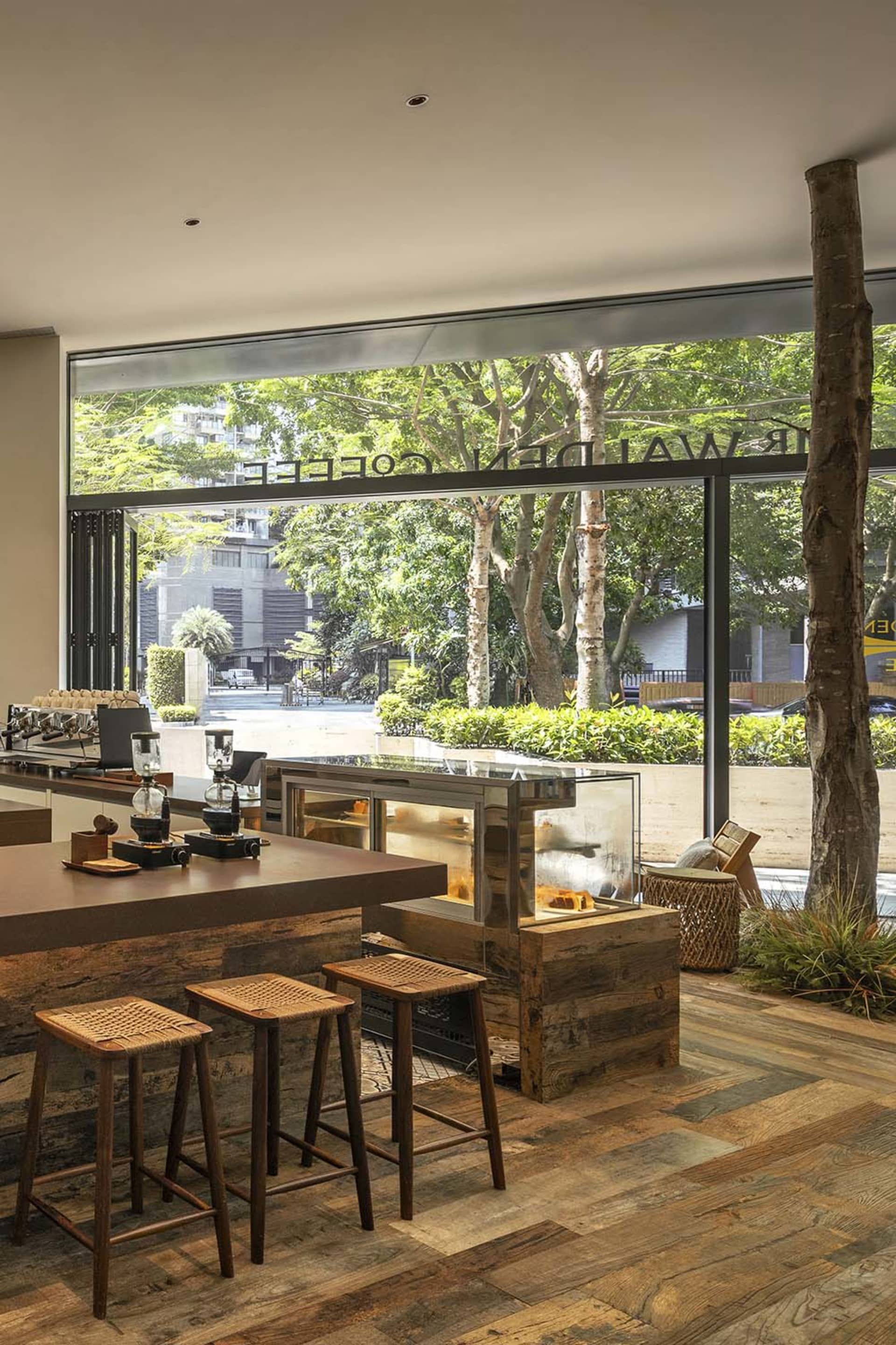 Industrial-style coffee shop interior with wood finishes and a large window displaying trees.