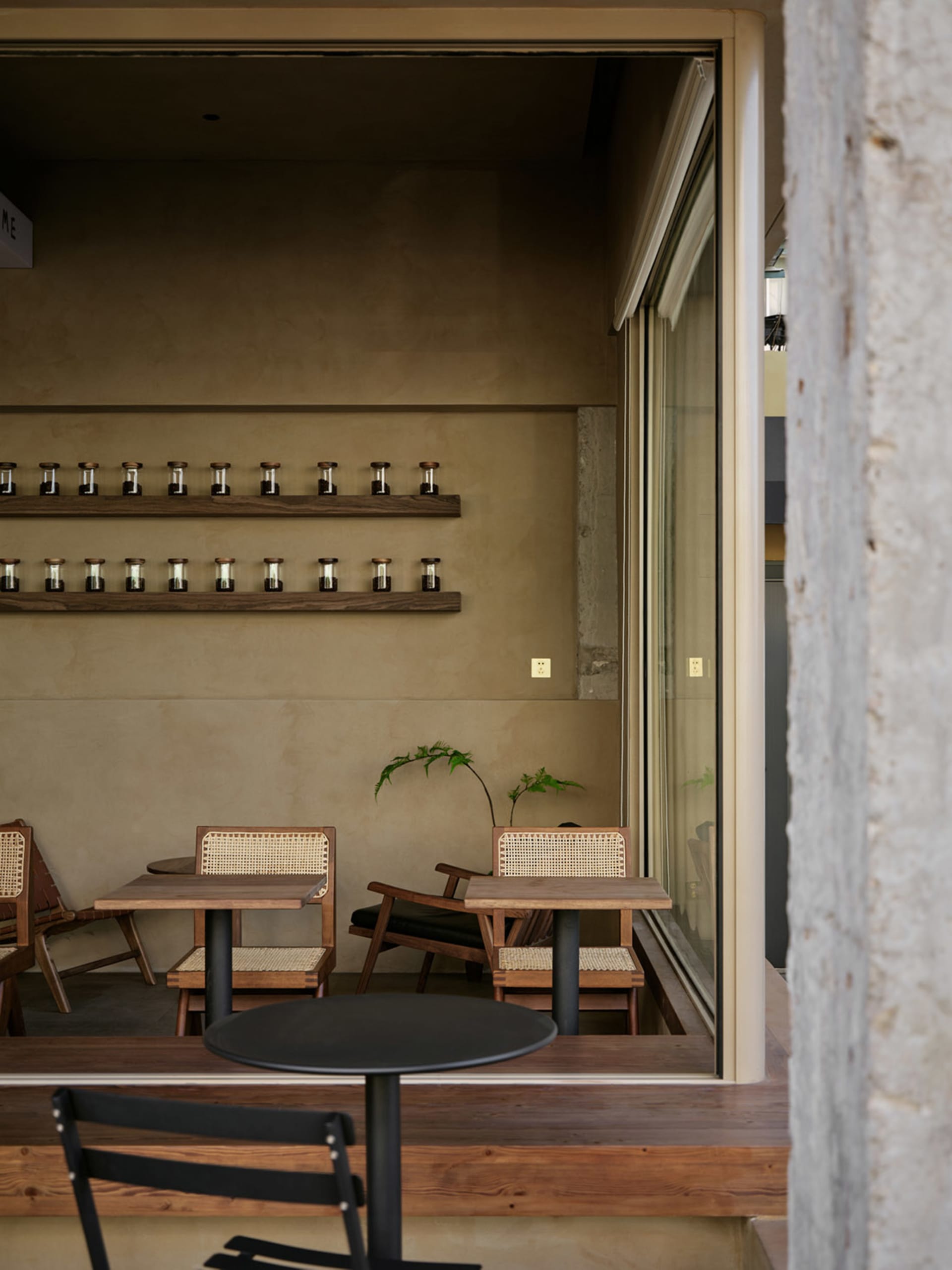 A modern industrial coffee shop interior with concrete walls and tables, featuring wooden chairs and a minimalist design.