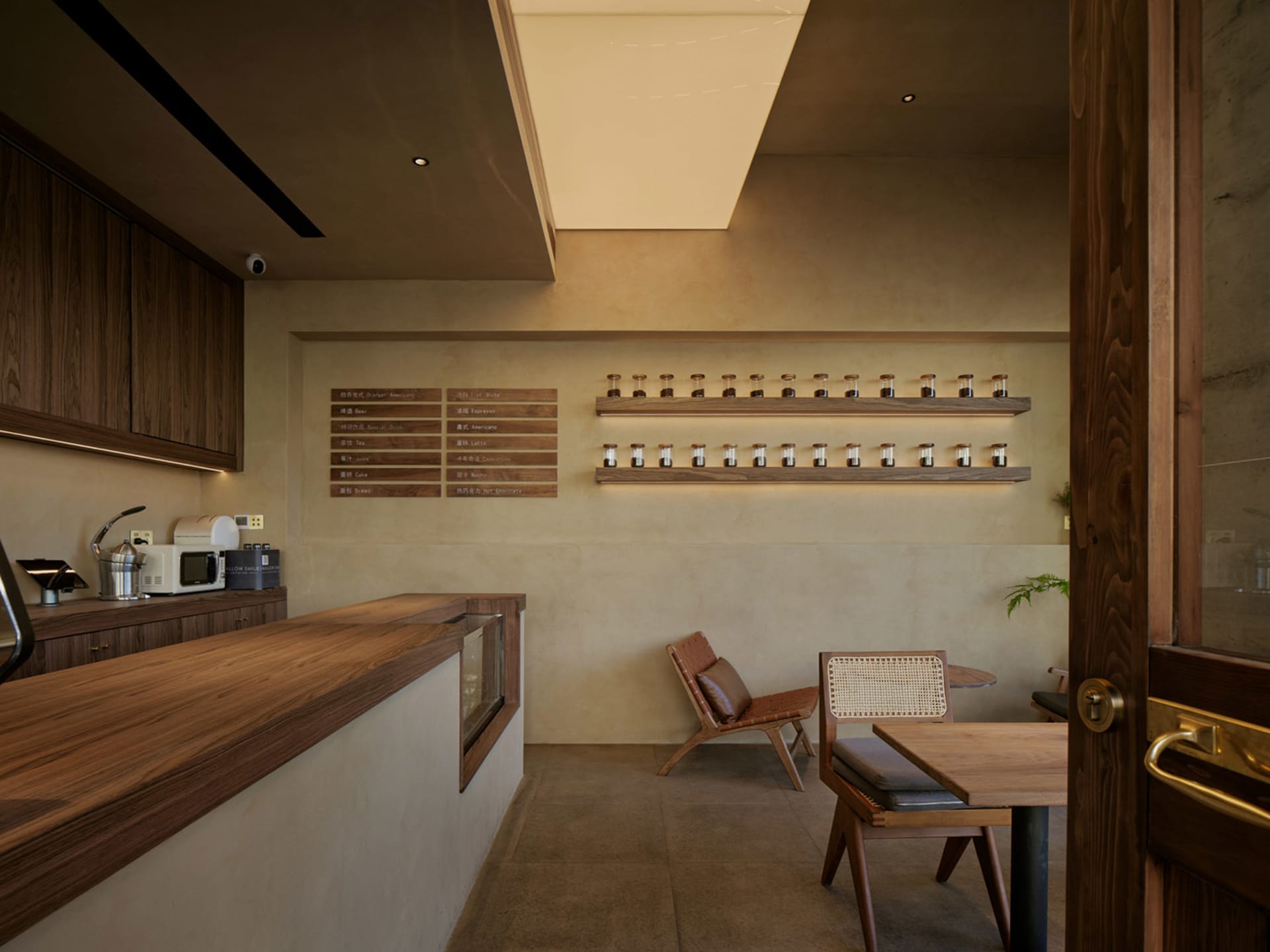 A minimalist coffee shop with a wooden counter, chairs, and a menu board.