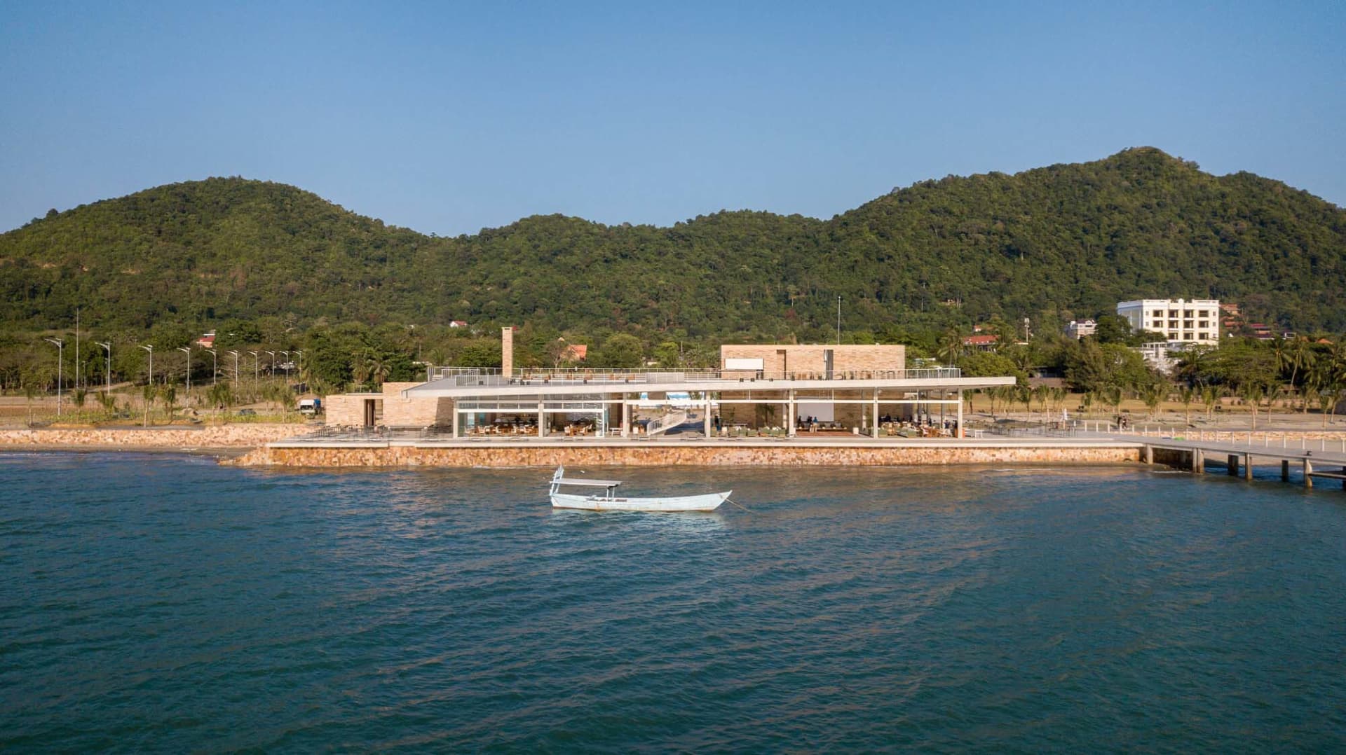 A modern resort entrance featuring a brick and concrete structure with a large overhang and a small boat in the foreground.
