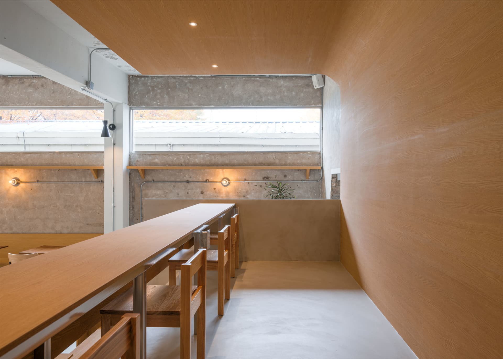 Industrially designed cafe interior featuring concrete walls and wooden furniture.