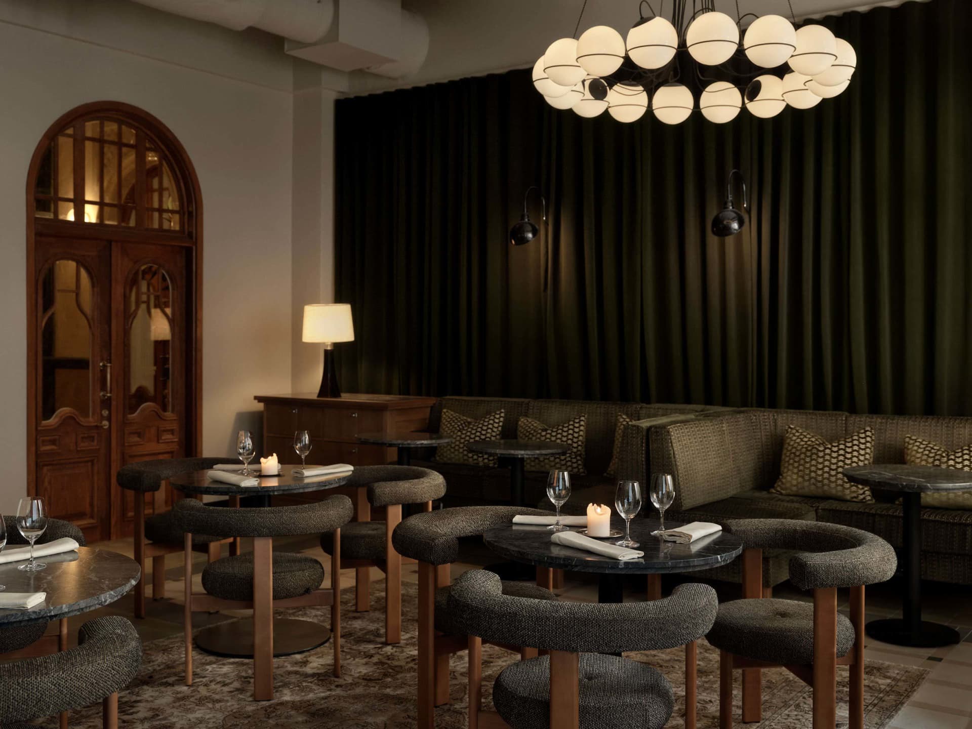 Industrial style restaurant interior with round tables, wooden chairs, and a chandelier