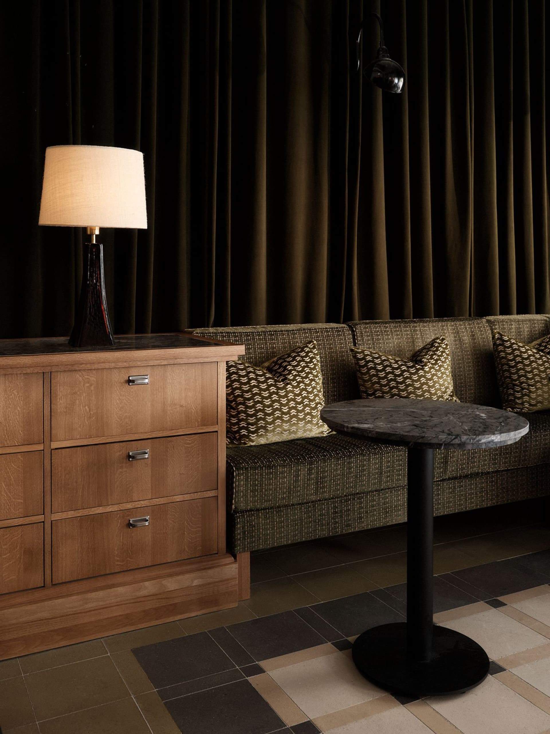 Modern living room with wood cabinet, marble table, green sofa, and fabric pillows.