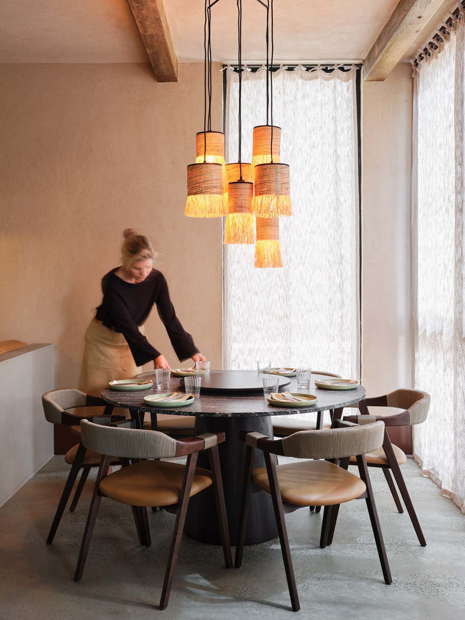 An industrial dining room with round table, chairs, and pendant lights.