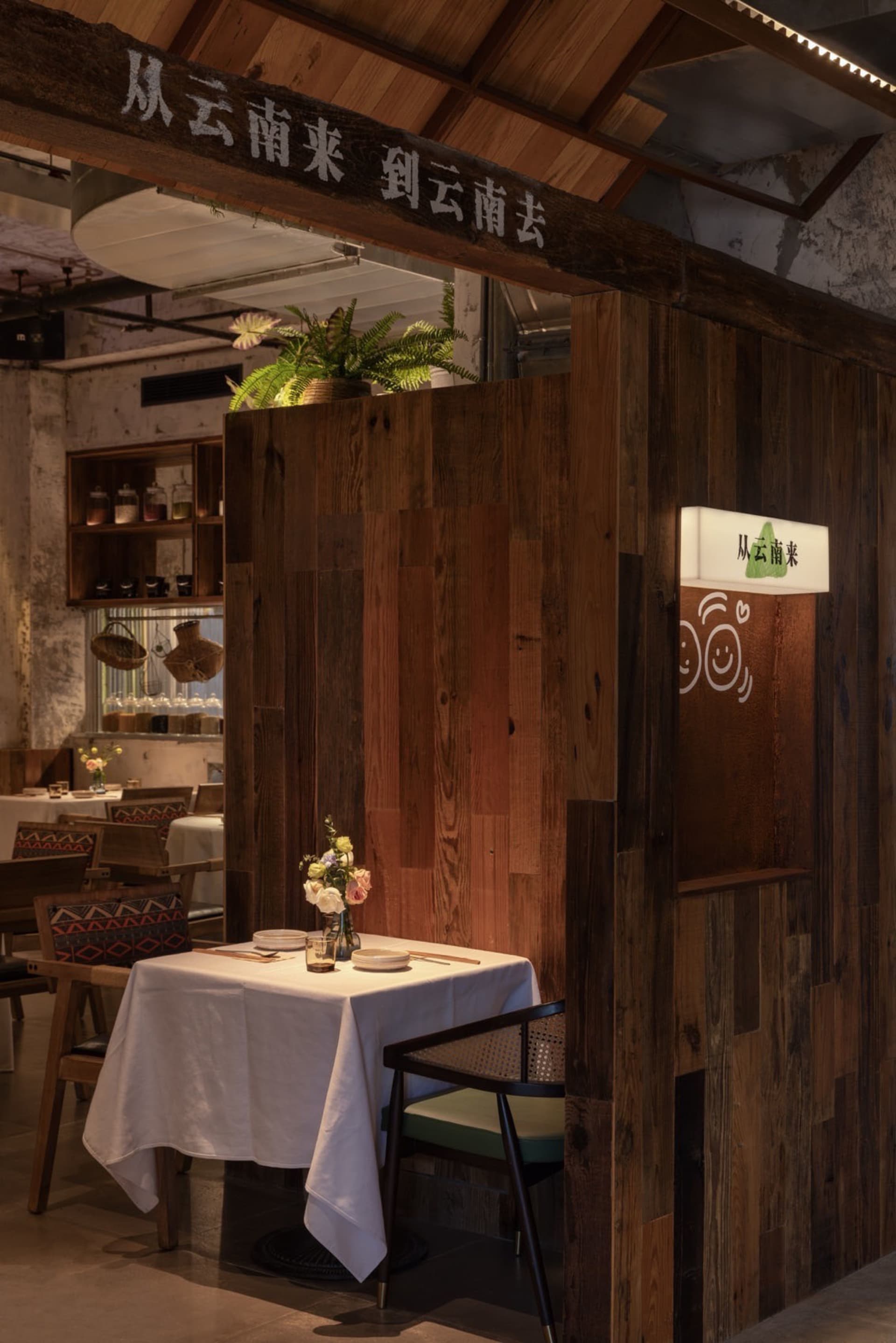 A cozy, industrial-style restaurant interior with wooden walls and a table setup.