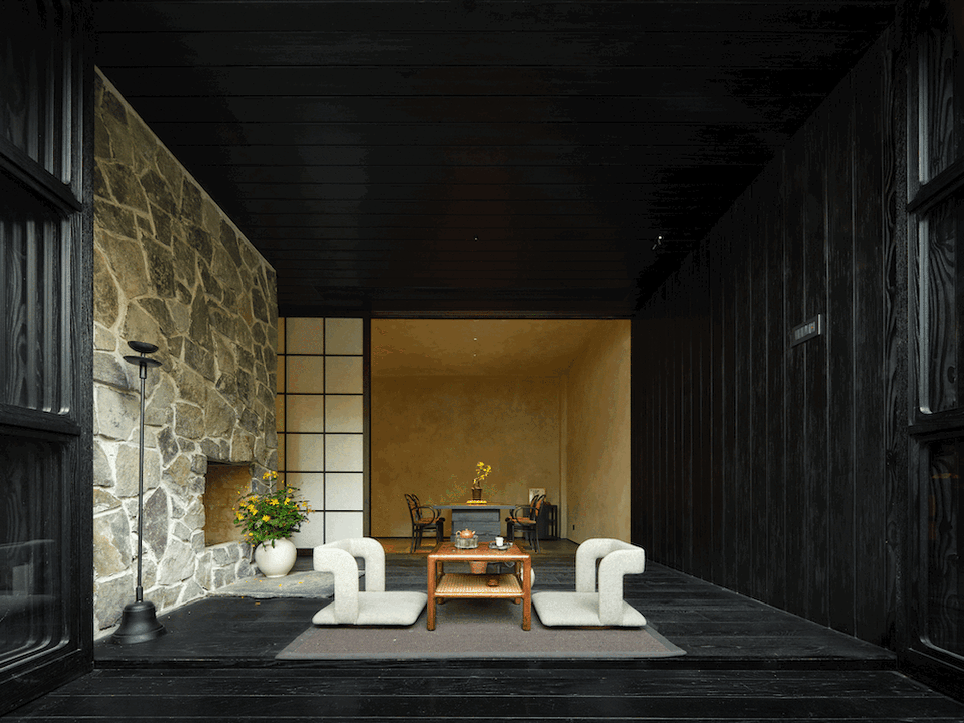 A modern living room featuring wooden furniture, a stone accent wall, and a cozy seating arrangement.