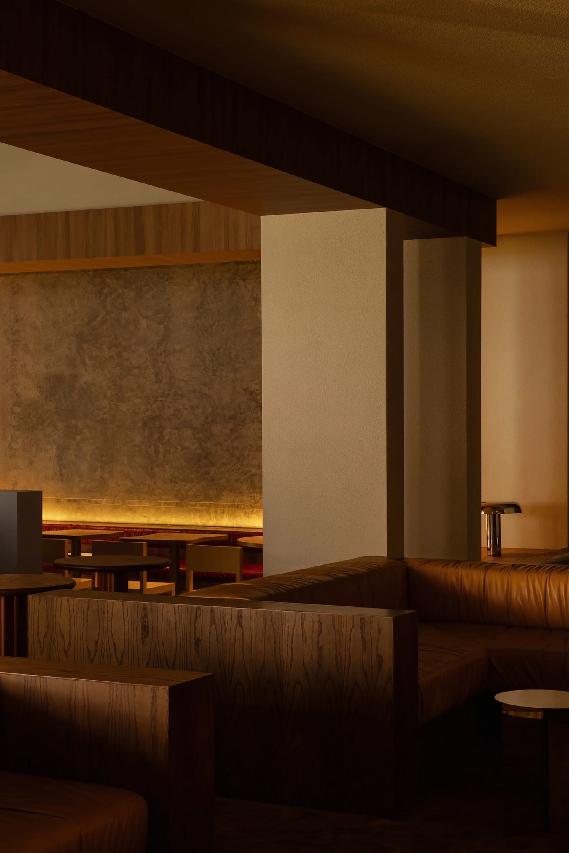 A modern restaurant interior featuring wooden booths, leather seating, and concrete accents.