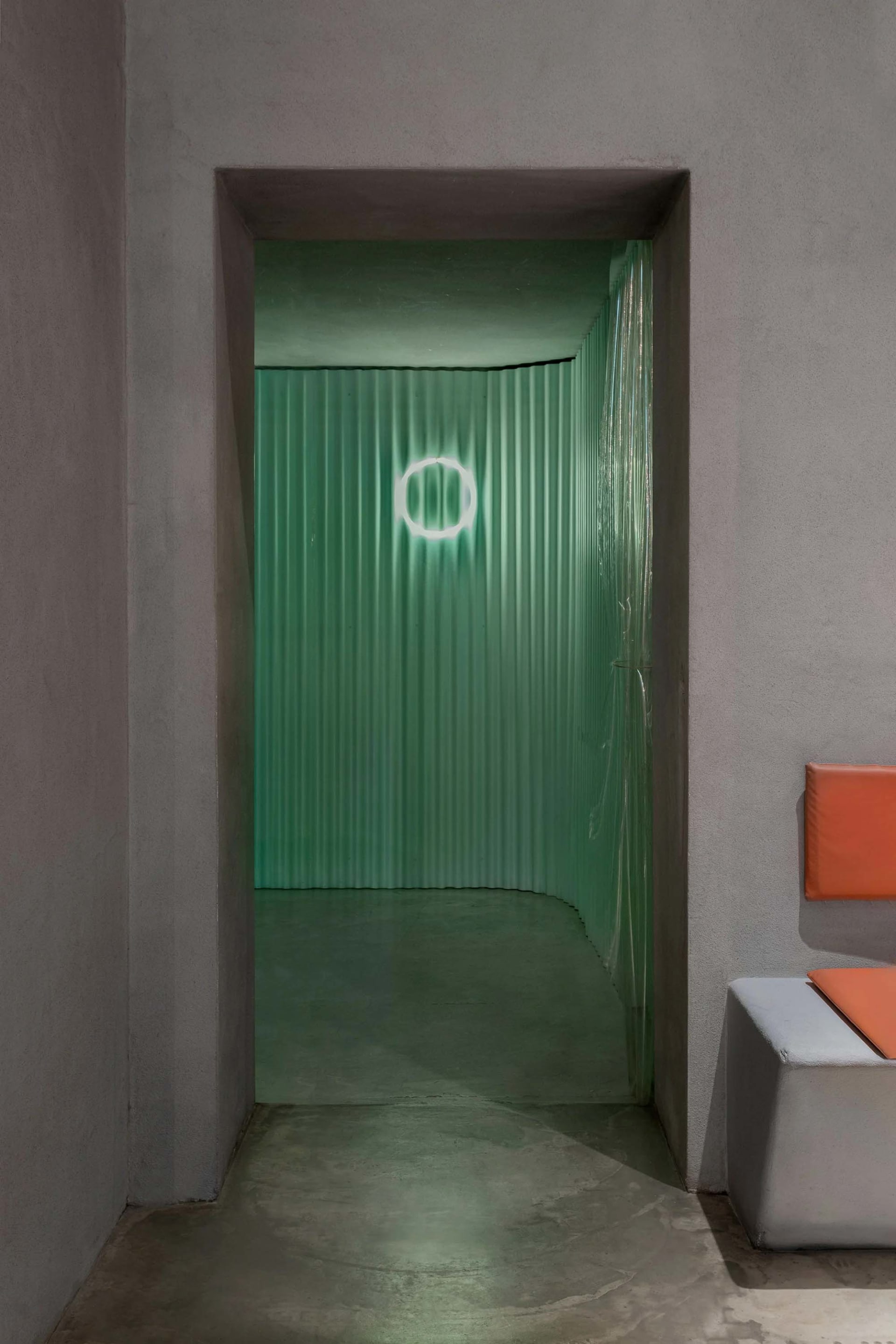 A minimalist corridor with corrugated metal walls and a circular light fixture