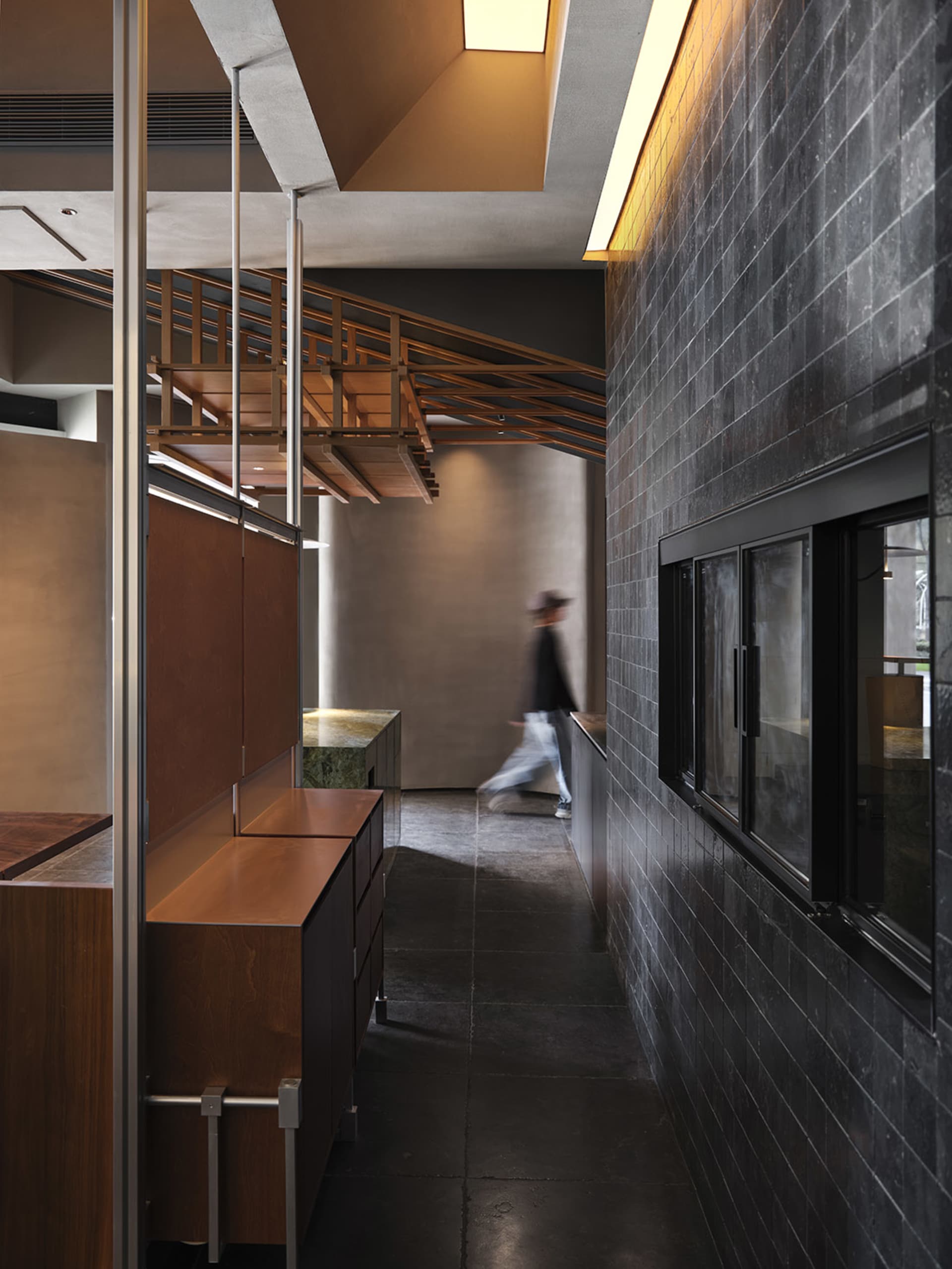 Modern industrial hallway featuring minimalist design with concrete and brick walls, wooden railings, and sleek metal accents