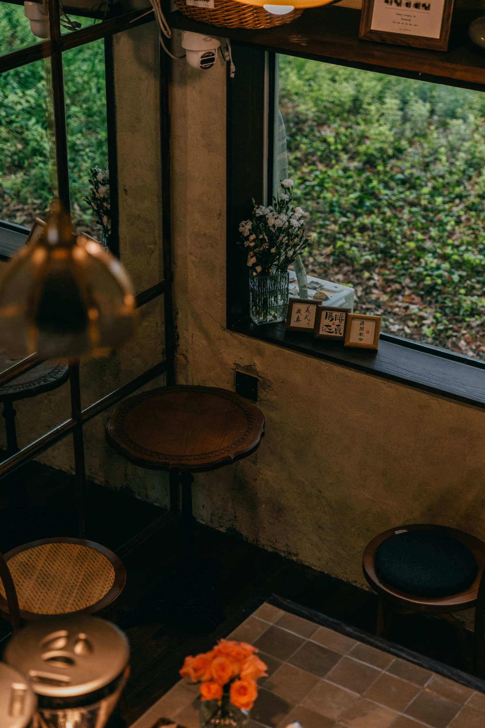 Modern cafe interior with wooden tables, glass vase with white flowers, and fabric-covered seating.