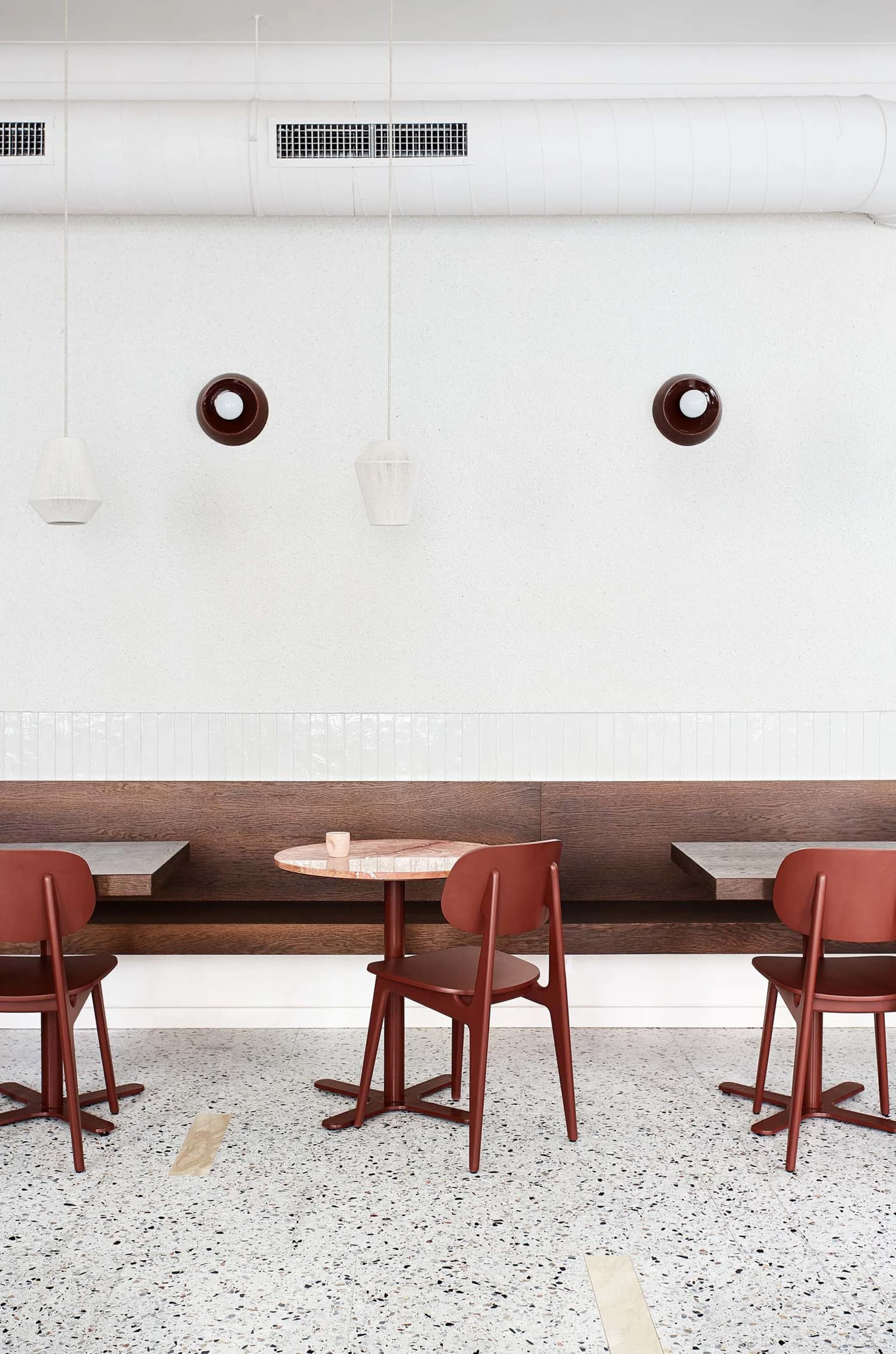 A modern coffee shop with a round pink marble table and terrazzo flooring.