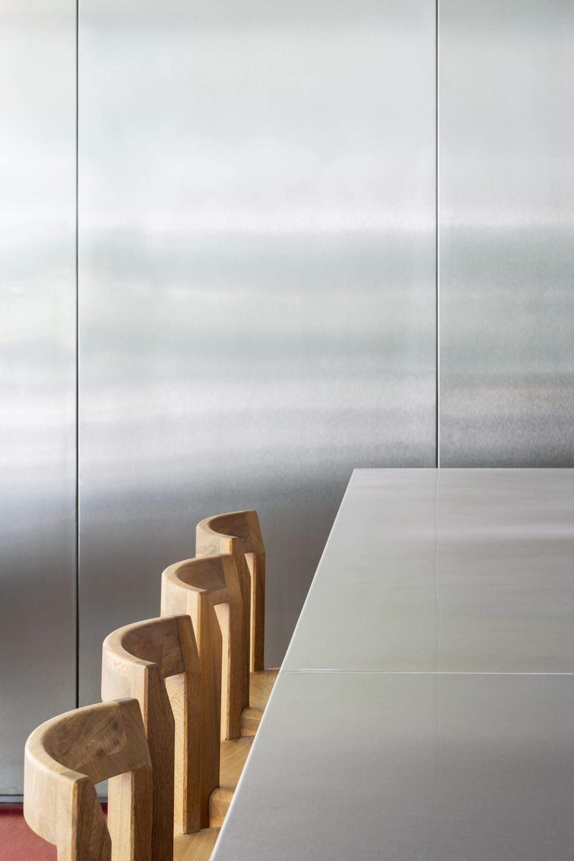 Modern interior featuring metallic furniture chairs arranged around a sleek metallic dining table.
