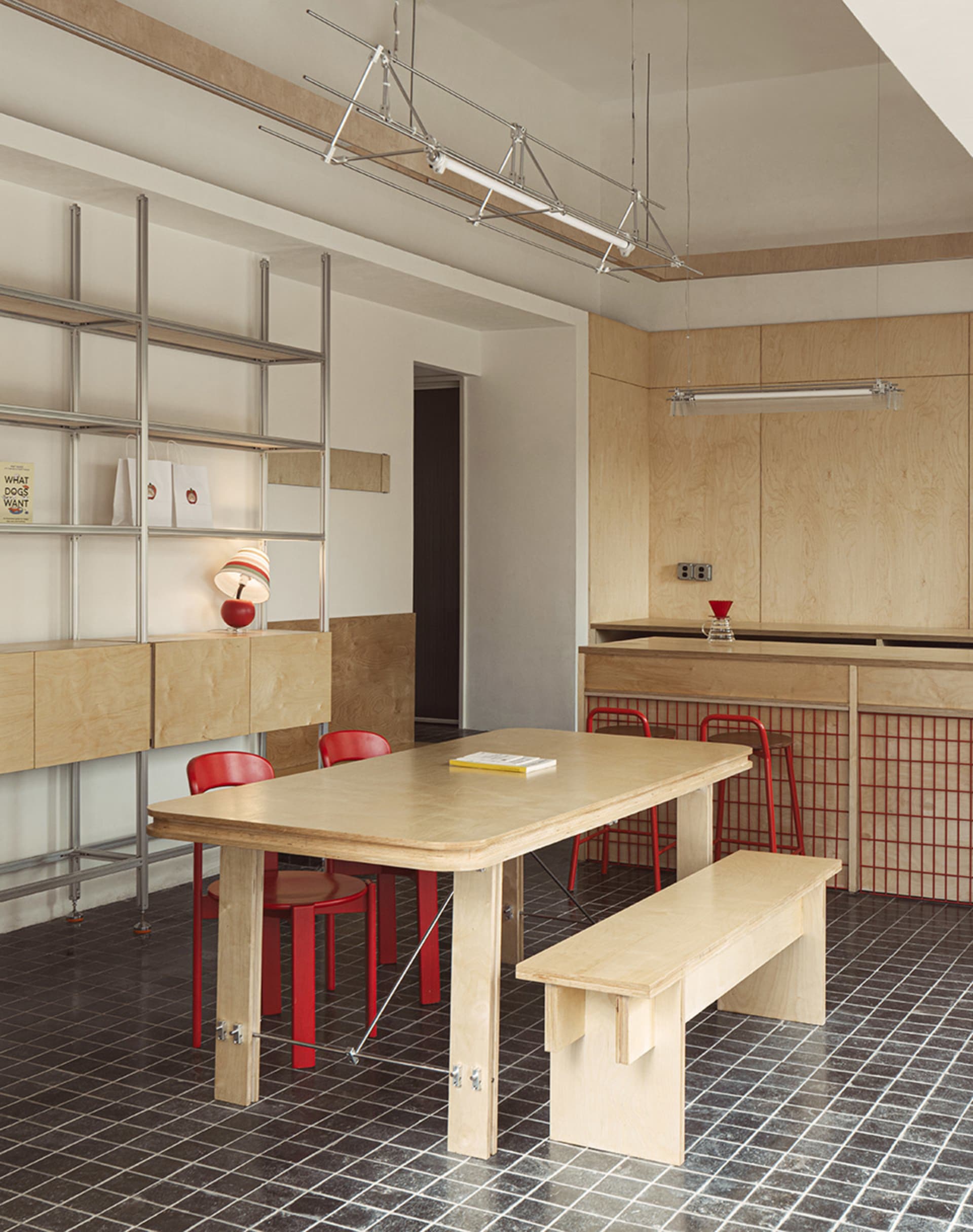 A minimalist commercial kitchen with wooden materials and a red chair.