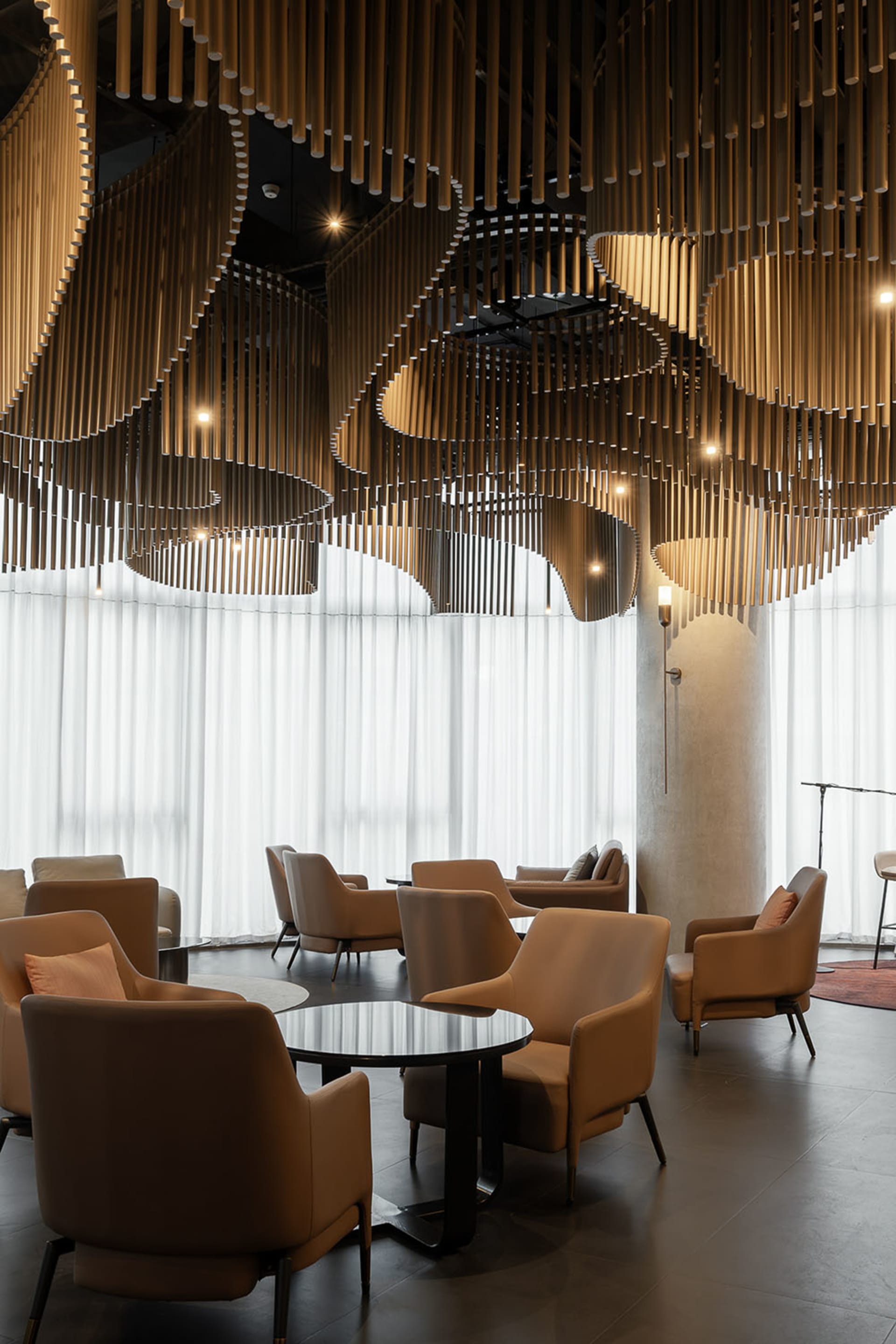 A modern lobby featuring wooden accent pieces and large windows with white curtains.