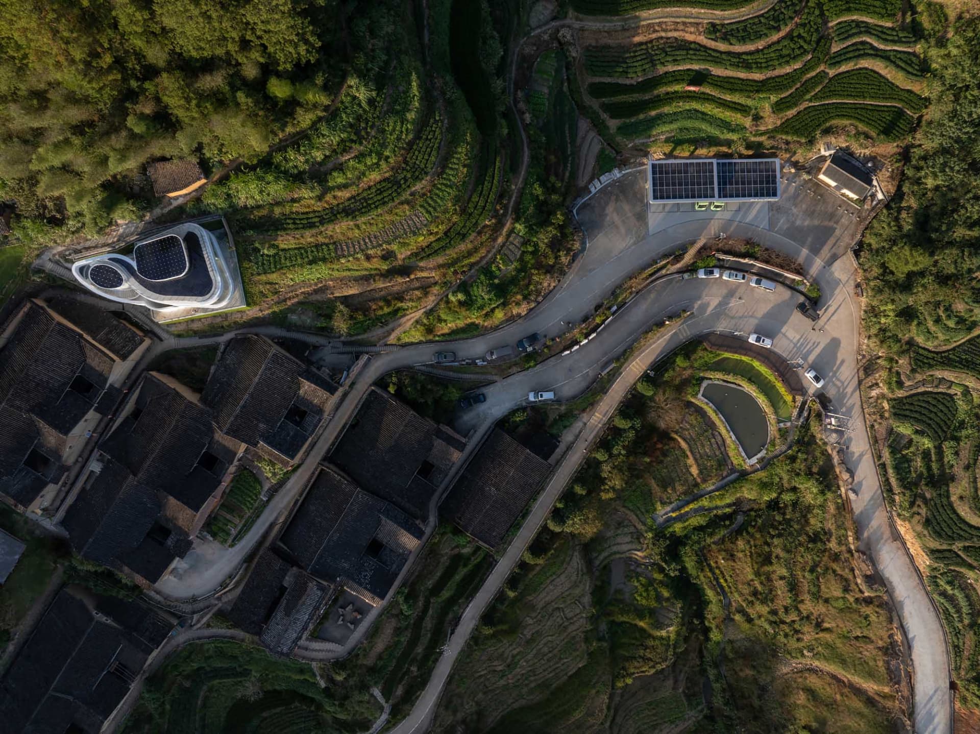 俯瞰山坡村落梯田，蜿蜒道路與太陽能板。
