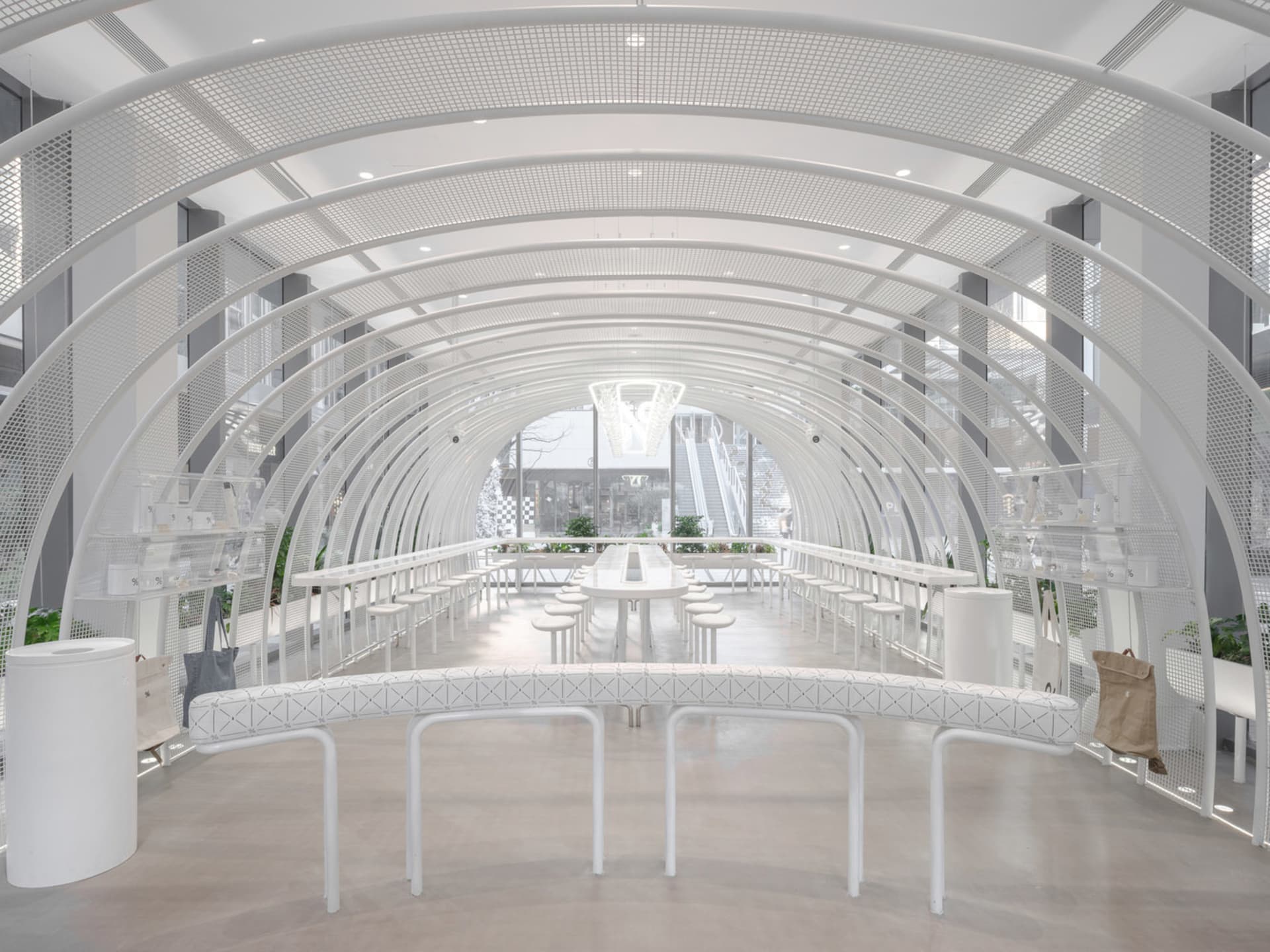 A minimalist restaurant with white arches, metal tables, and glass walls.